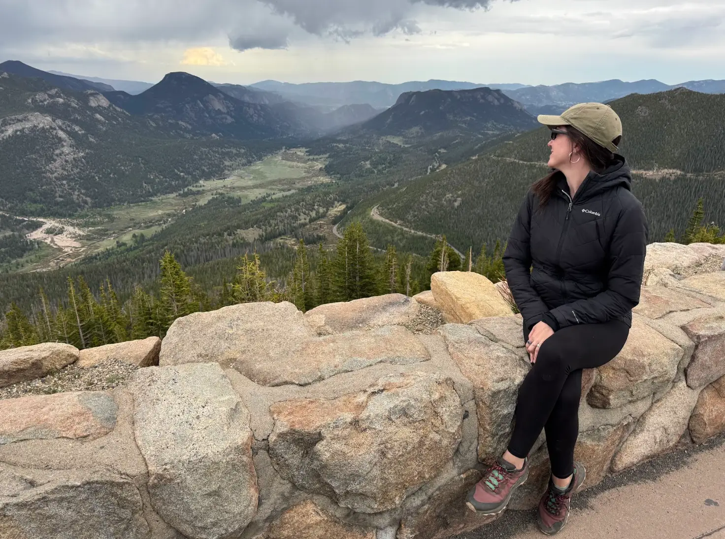 The writer wears hiking gear and sits on a ledge, overlooking a Colorado landscape.
