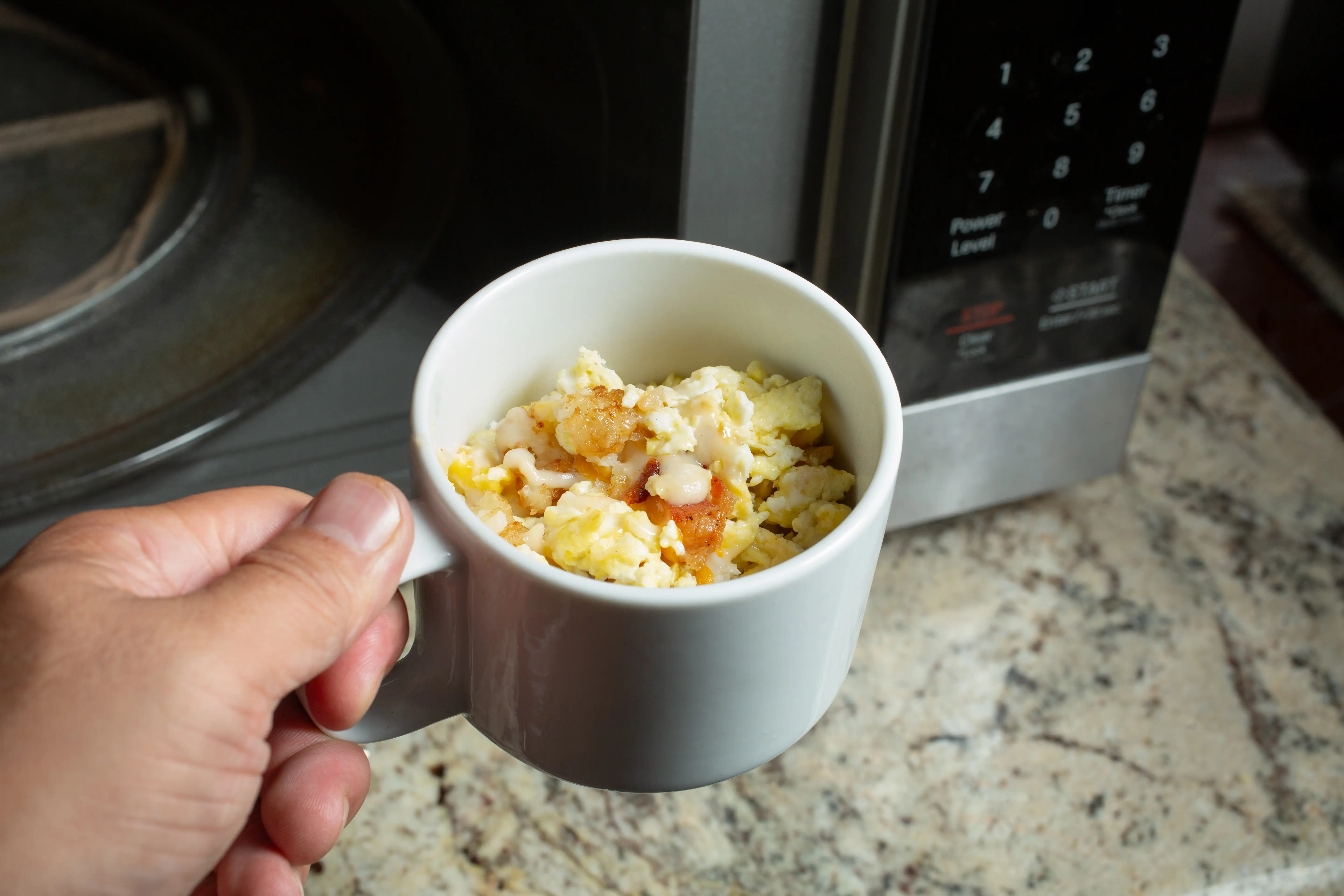 eggs with toppings in mug next to microwave