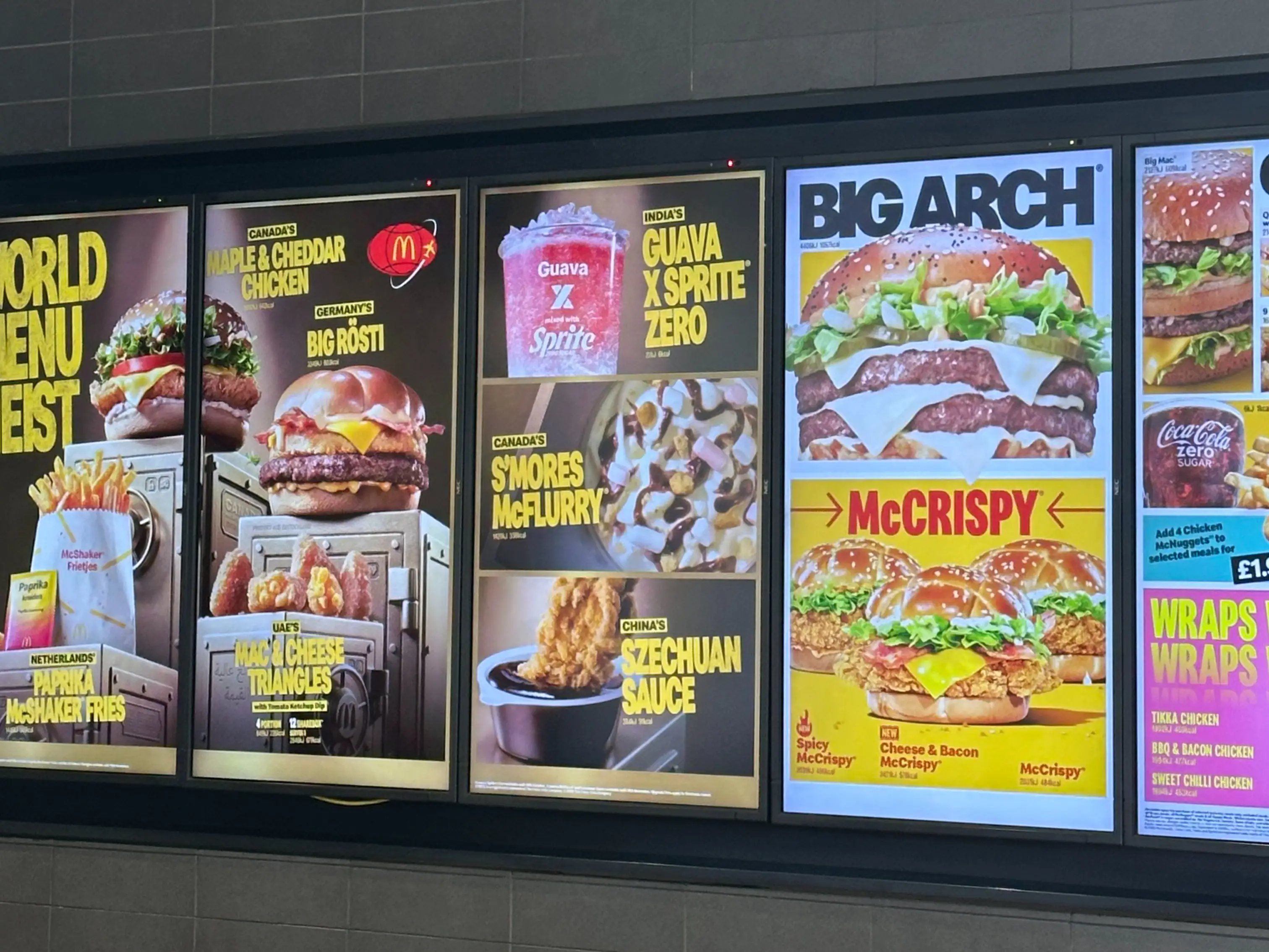 Illuminated McDonald’s menu boards advertise World Menu Fest items, Big Arch burgers, McCrispy sandwiches, drinks, and wraps.