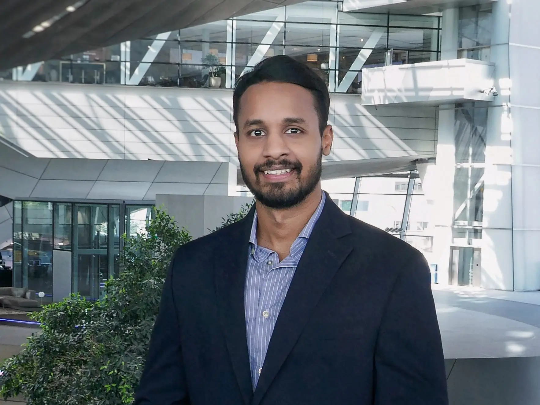 Ishansh Gupta is wearing a blazer, a blue shirt, and white trousers.