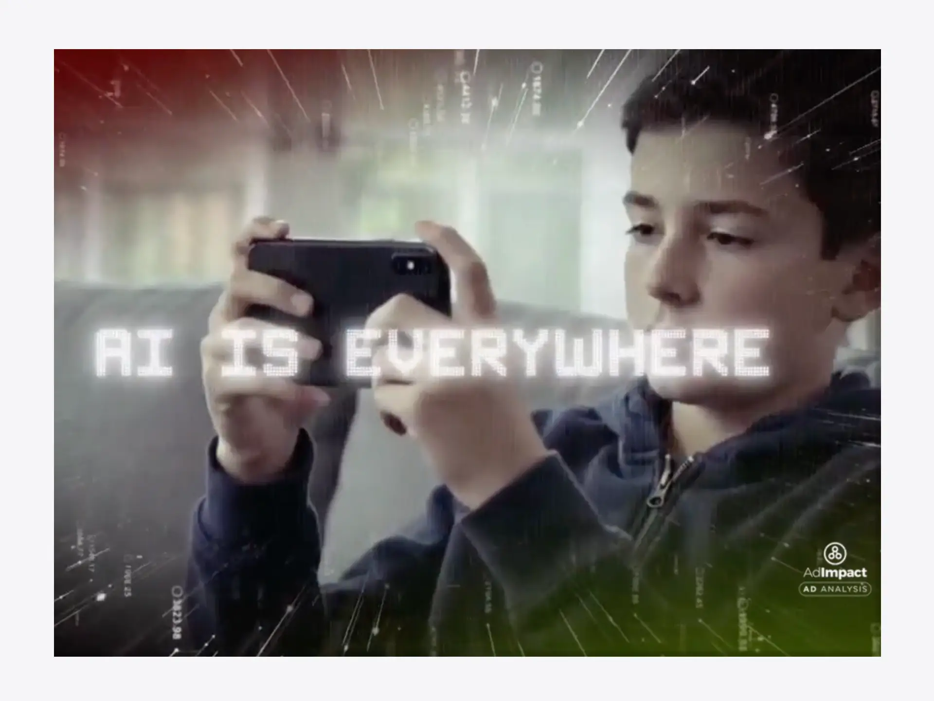 A boy holds up a phone in the background with 