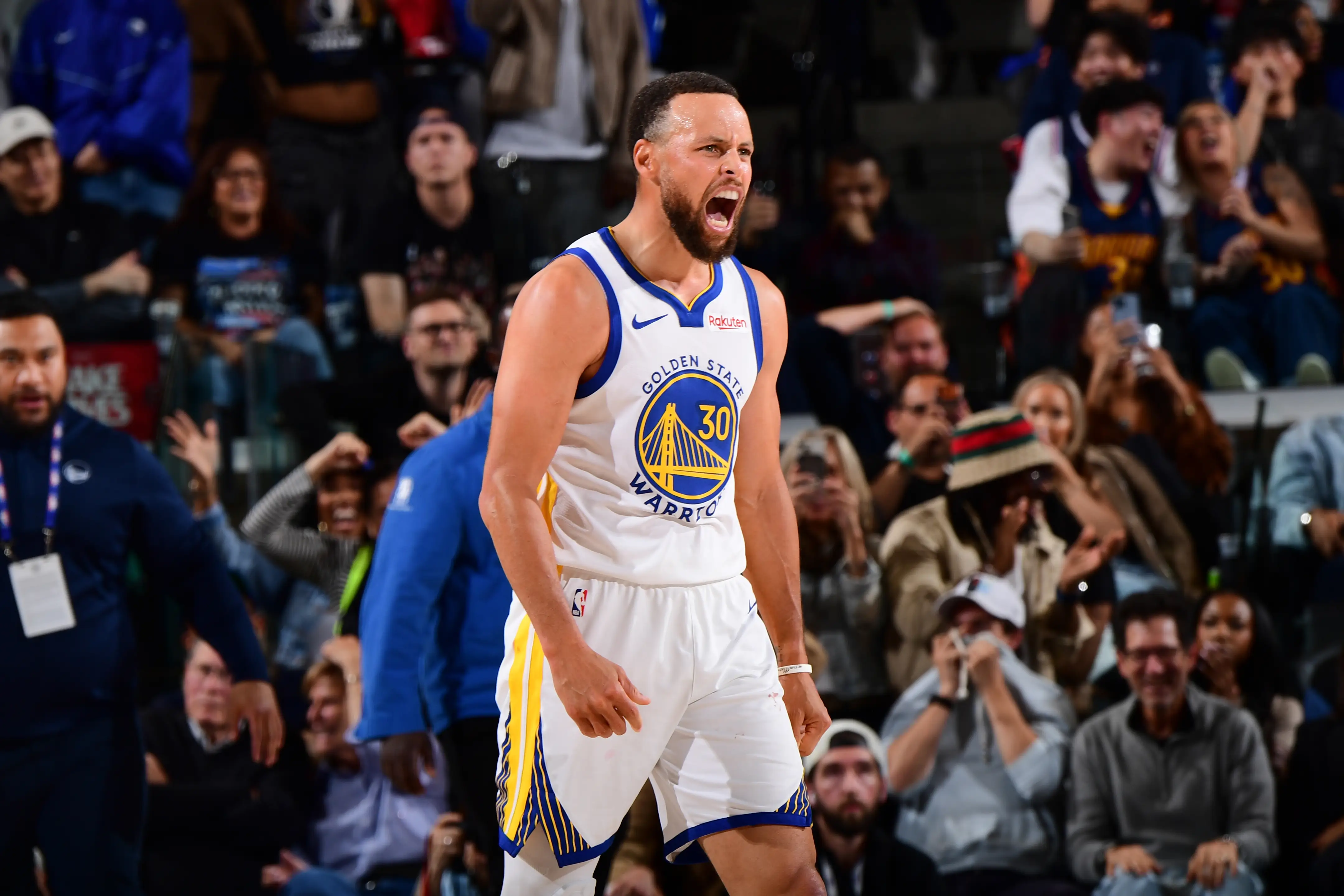 Stephen Curry reacts on the court in a Golden State Warriors uniform as spectators watch from the stands.