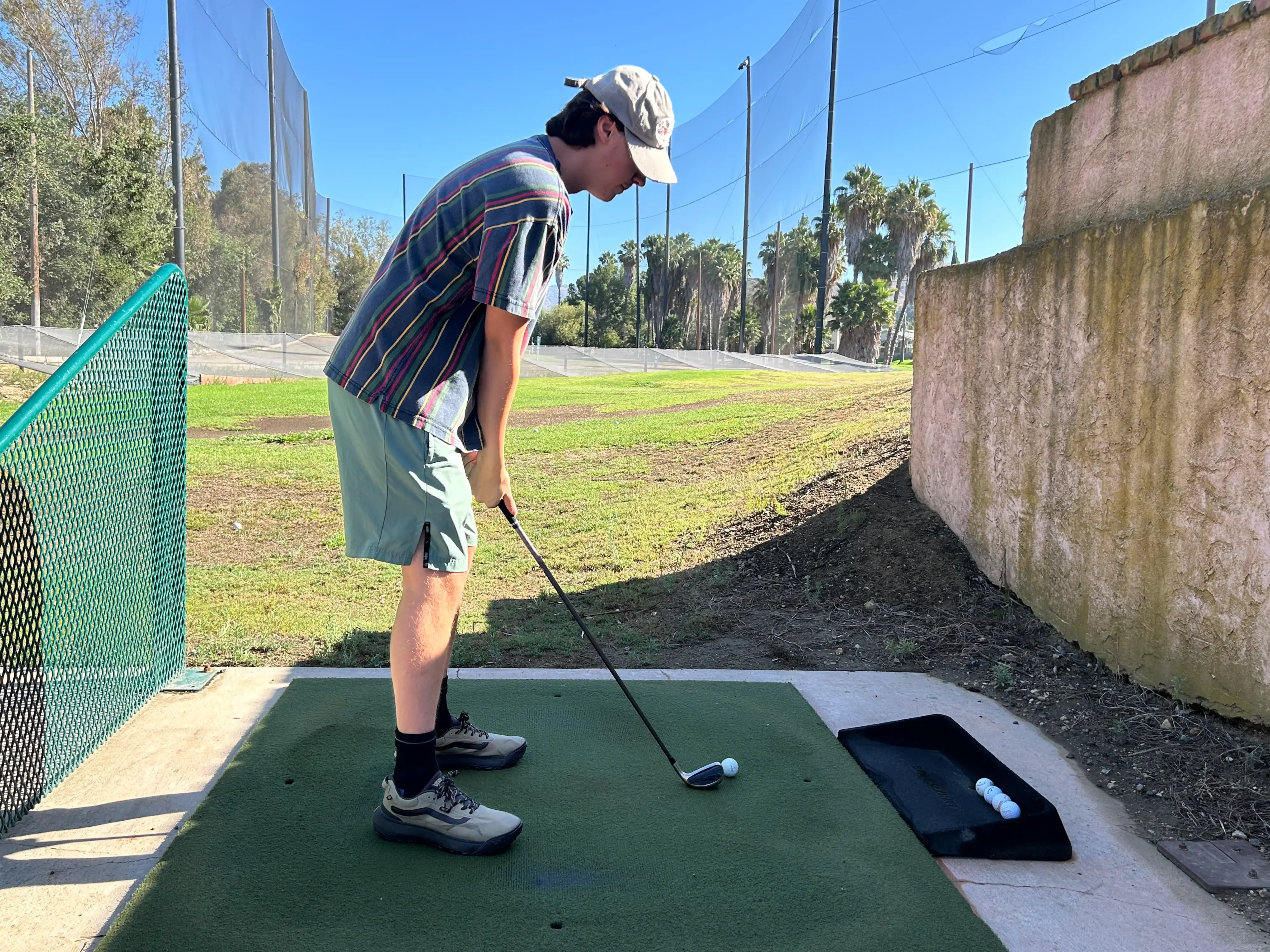 The author's son is shown while holding a golf club at a driving range.