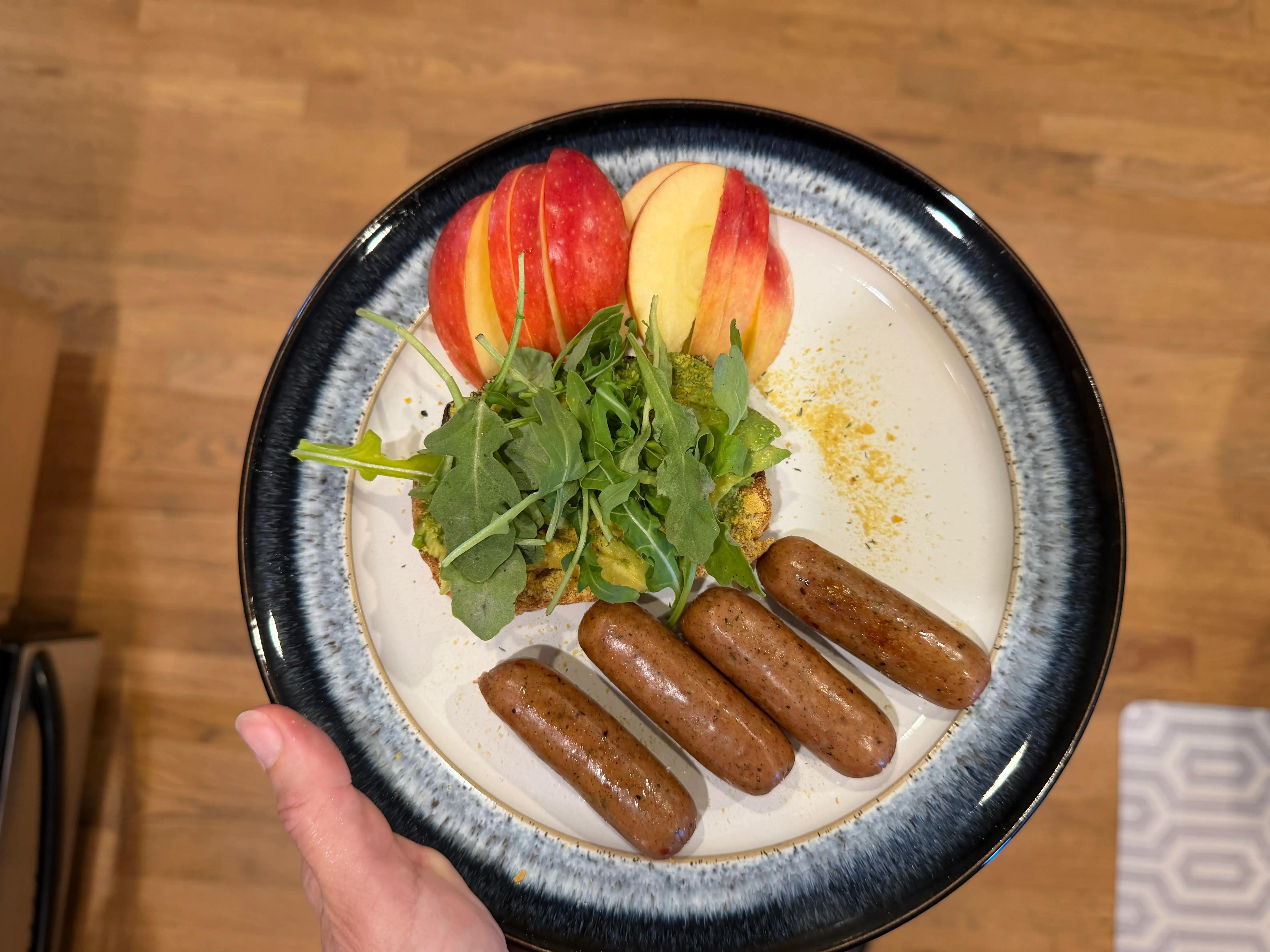 Sasuage, sliced apples, and avocado toast topped with greens on plate