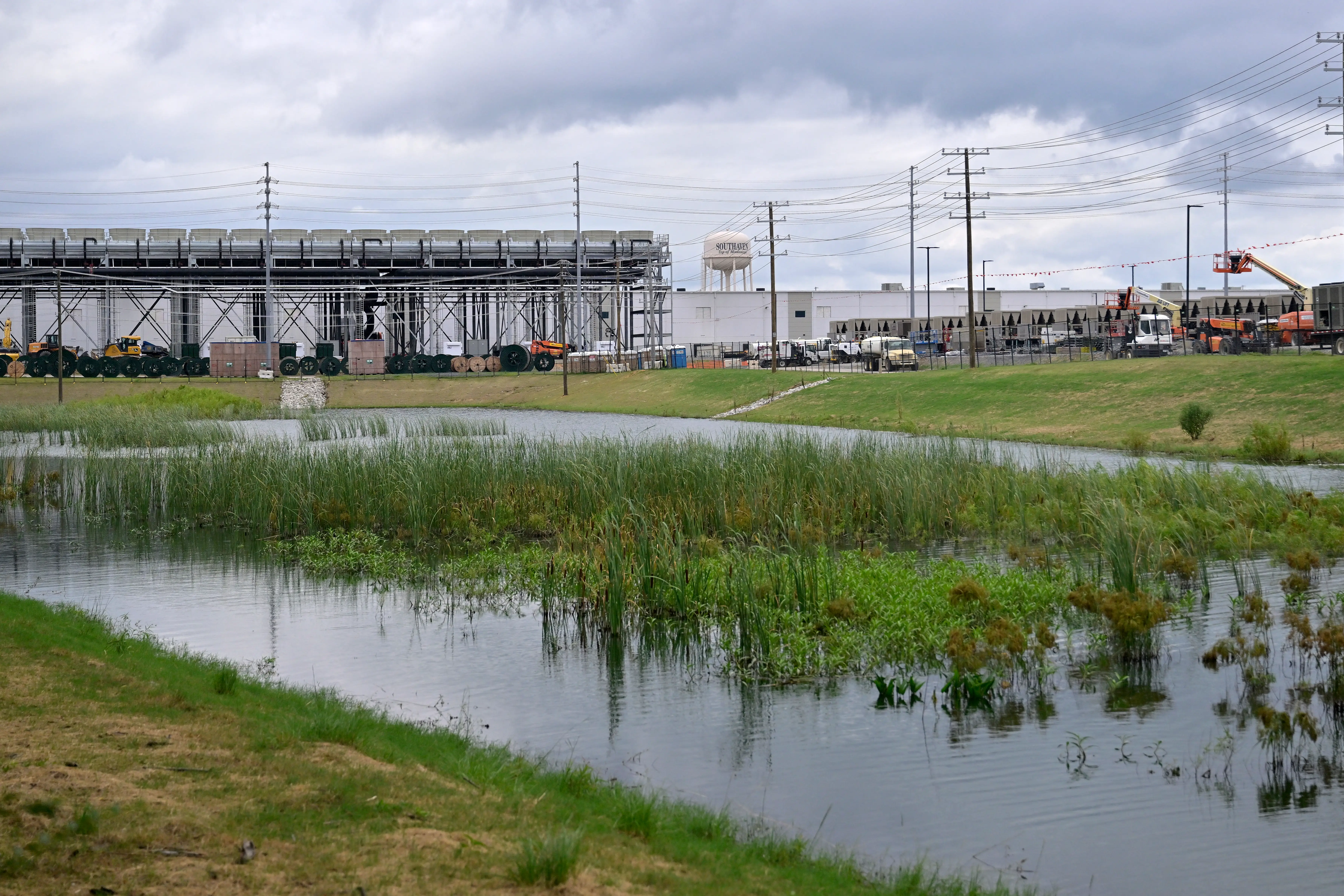A swampy lake in the foreground, with construction in the background.