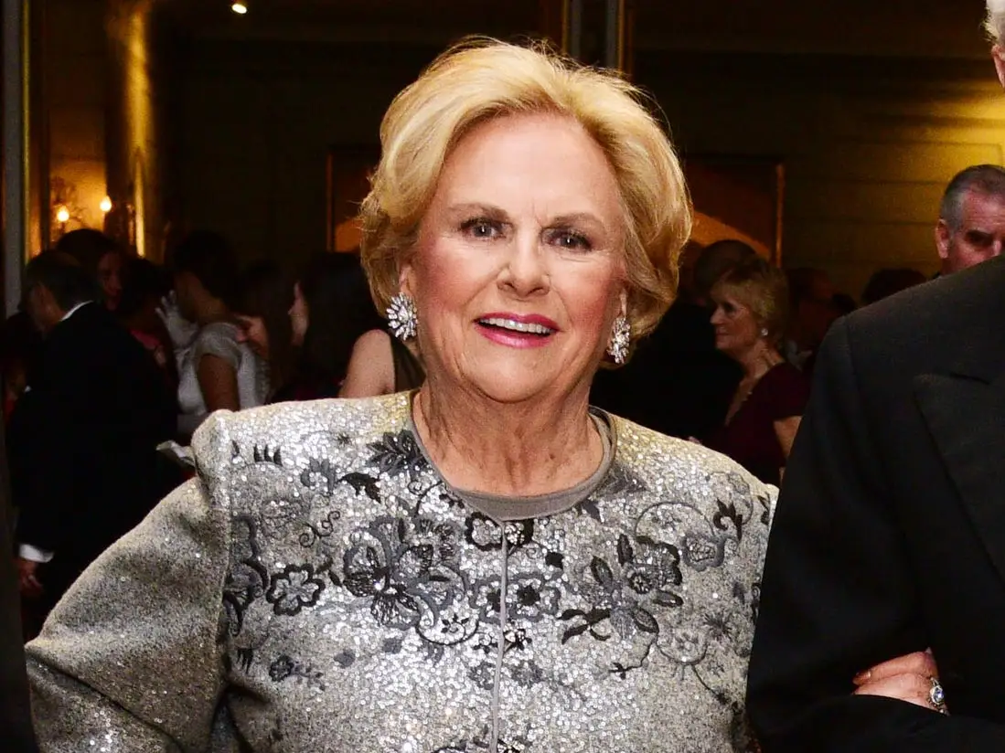 Three attendees in formal evening wear pose on a ballroom dance floor during a gala.