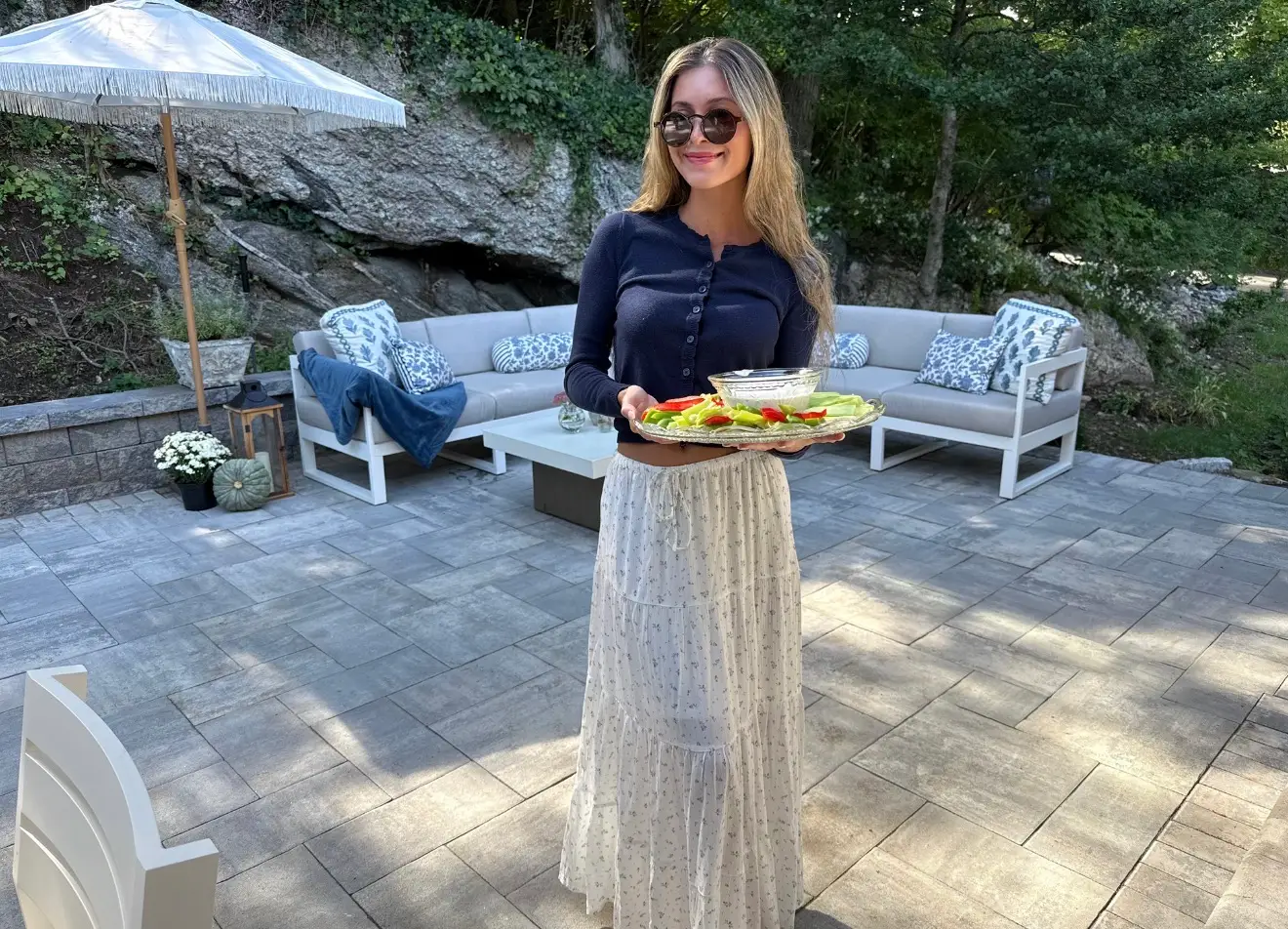 Woman holding tray of food on stone patio