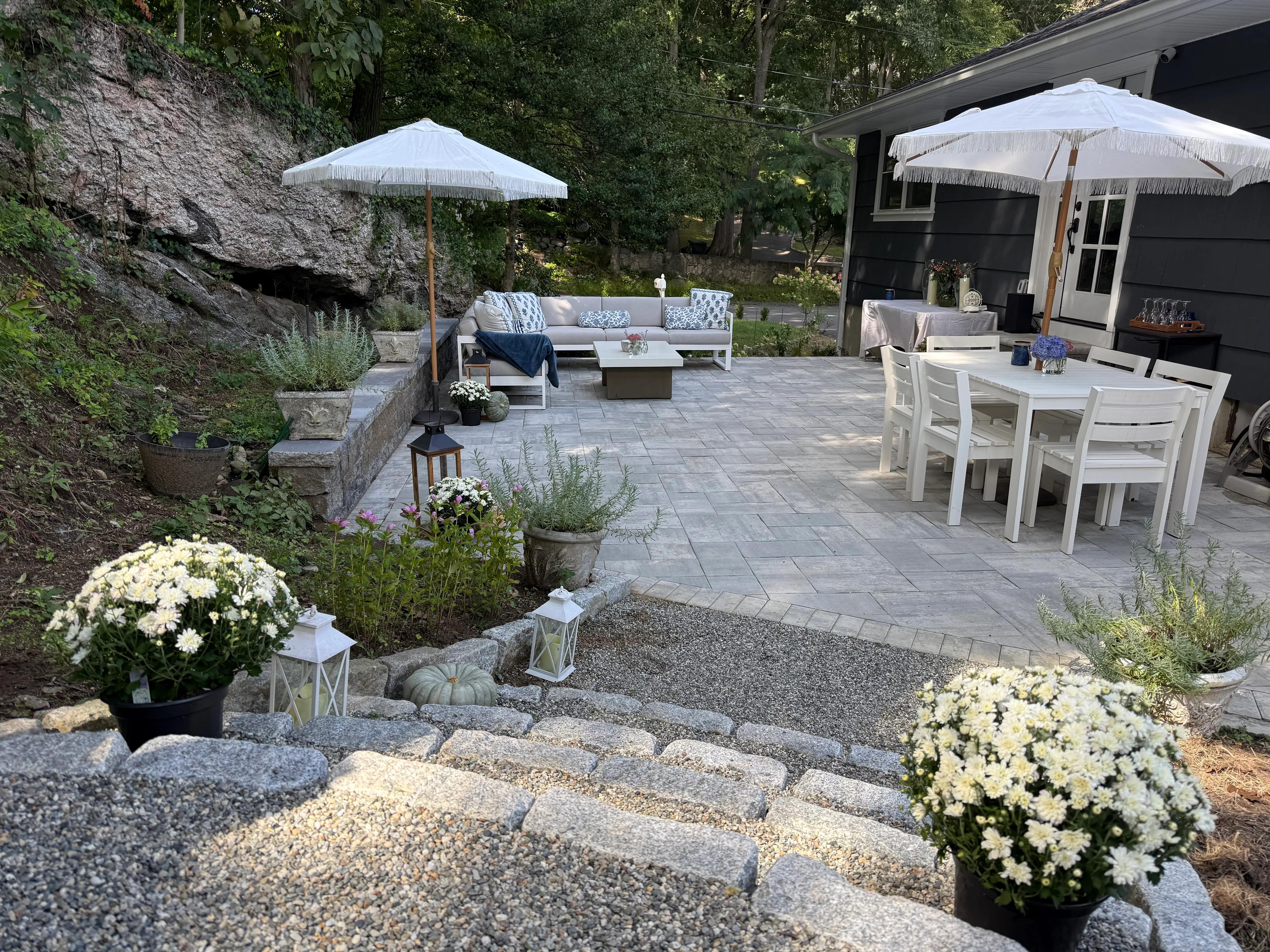 Stone patio with steps leading down to it, table and umbrellas