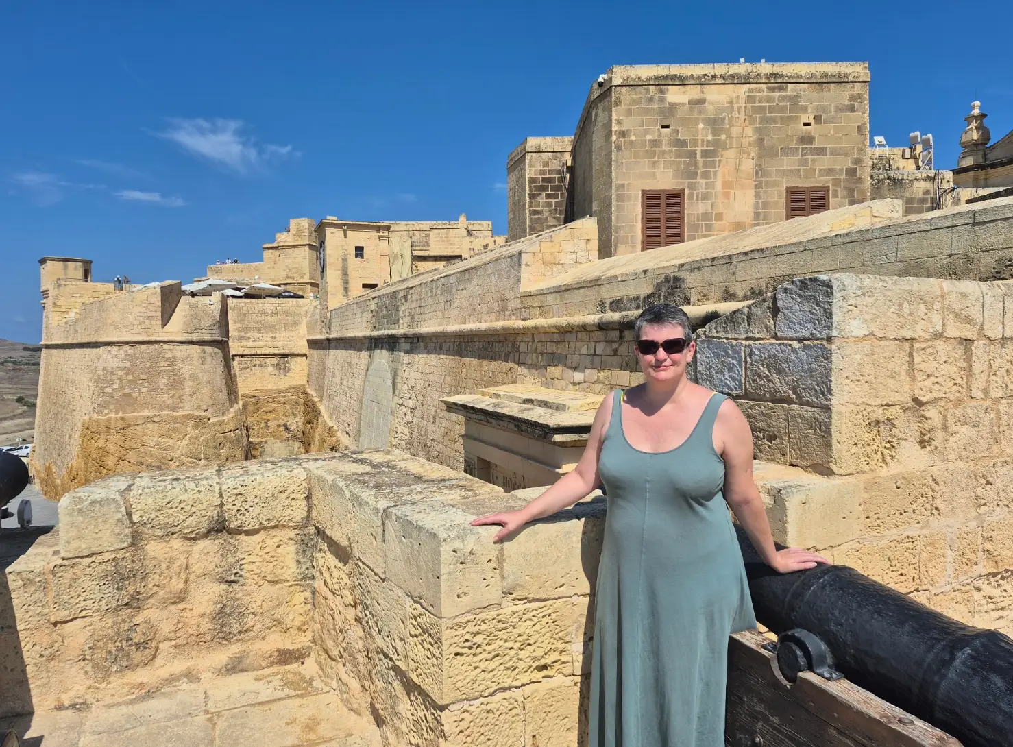 The writer wearing a dress and standing at the Citadel on Gozo.