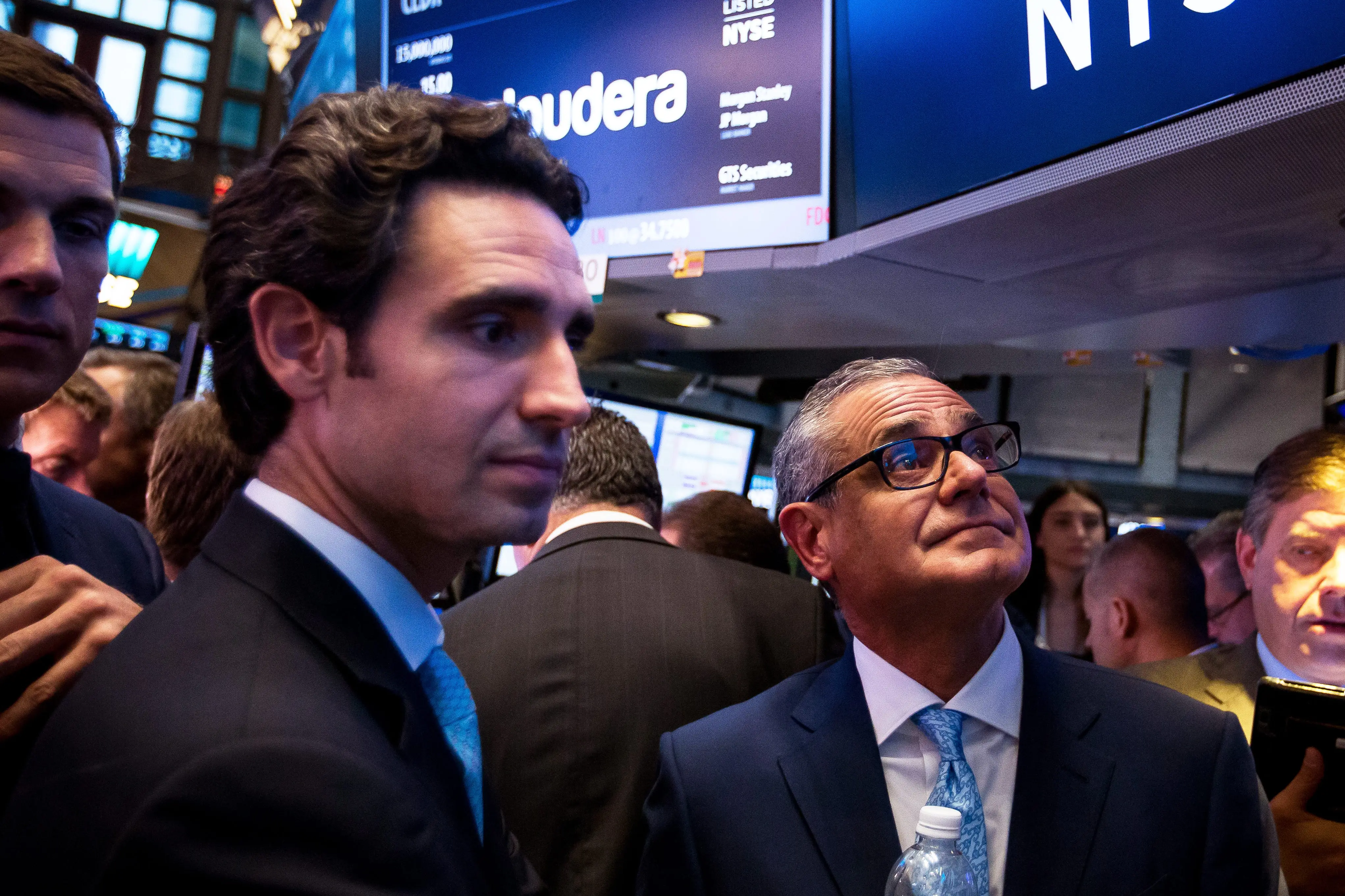 Crowded NYSE trading floor with traders and screens showing Cloudera stock information under large NYSE signage.