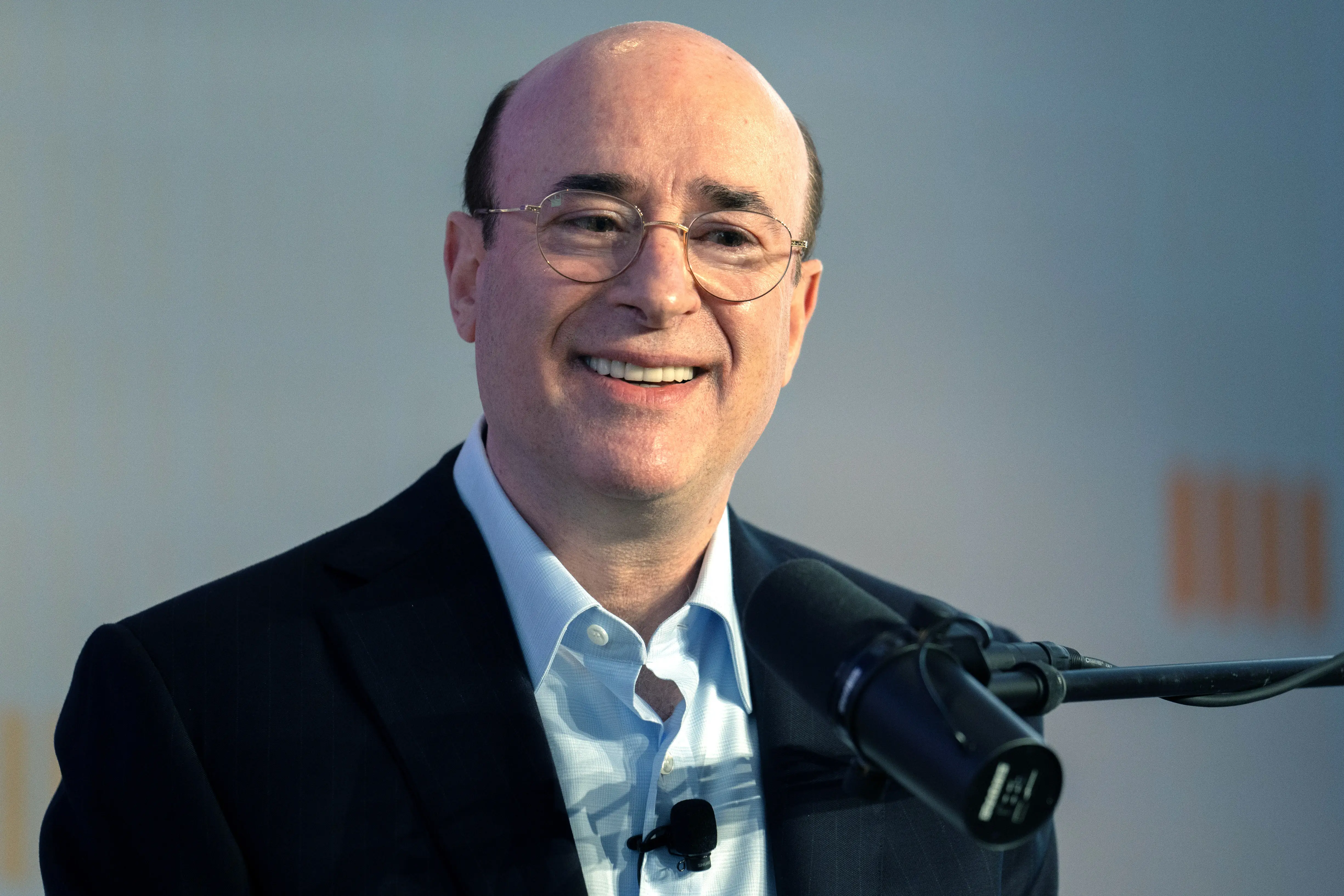 Brad Jacobs smiles while speaking at a podium microphone during an event.