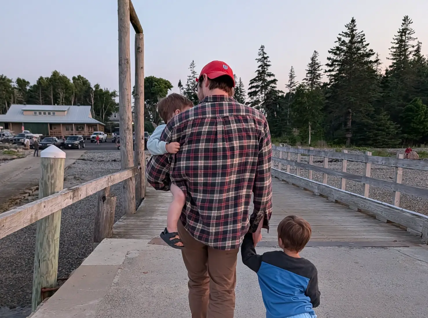 The writer's husband carries one boy and holds the other's hand as he walks down a dock.