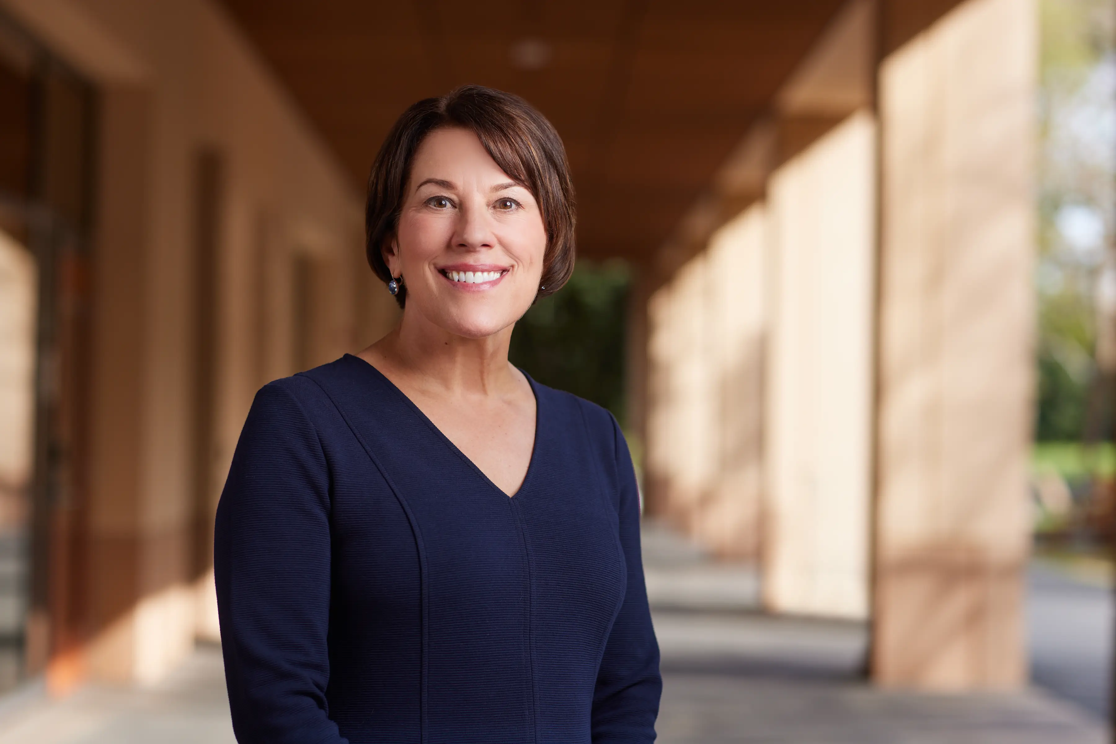 The dean of Stanford's graduate business school, Sarah Soule, stands in a colonnade.