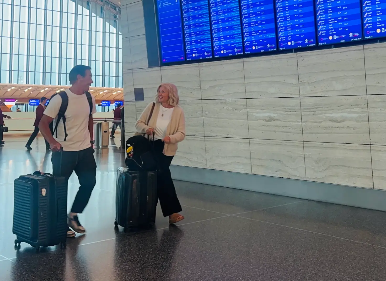 The writer and her husband rolling suitcases at an airport gate.