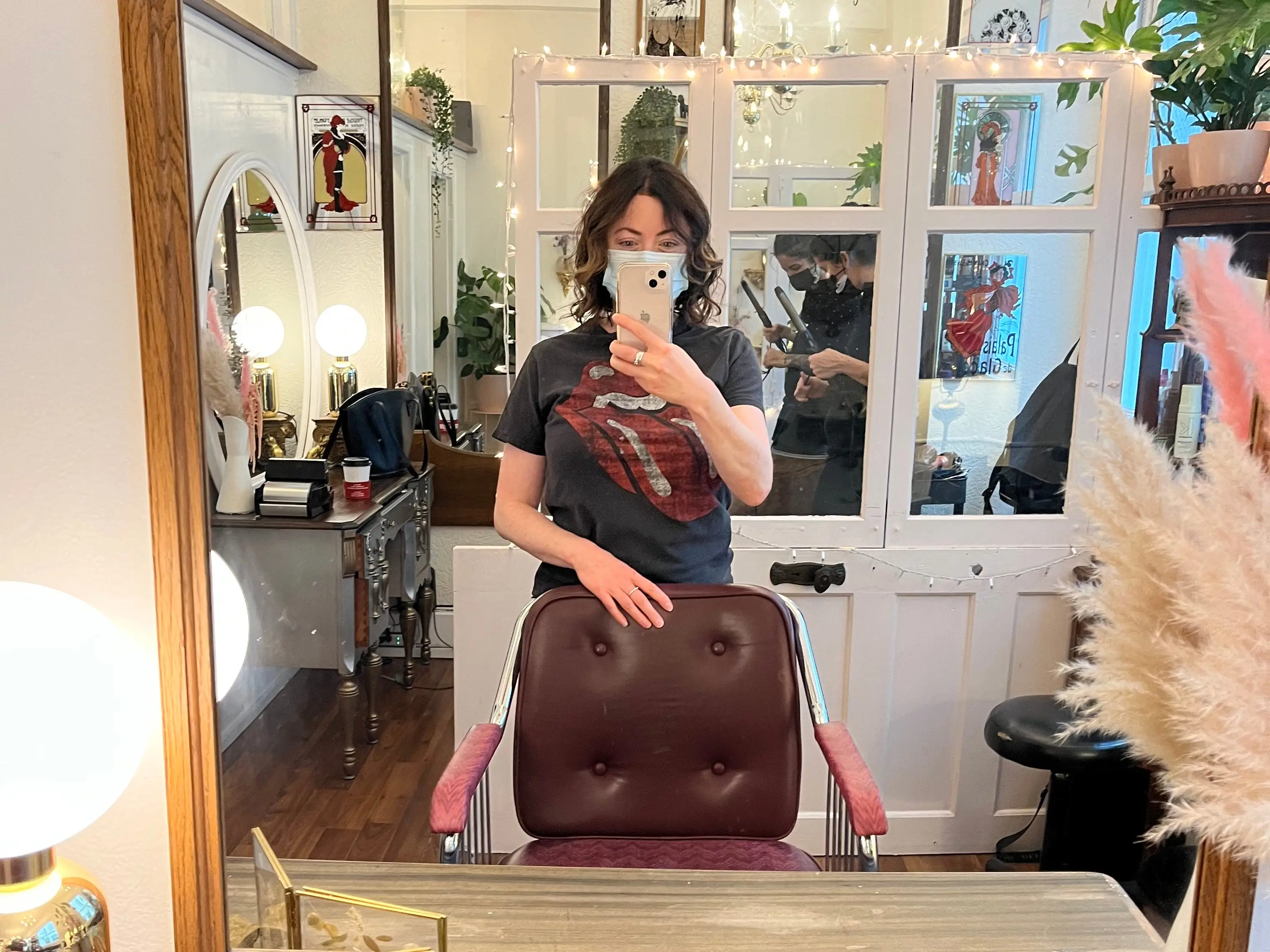 Woman taking selfie in salon mirror, holding chair