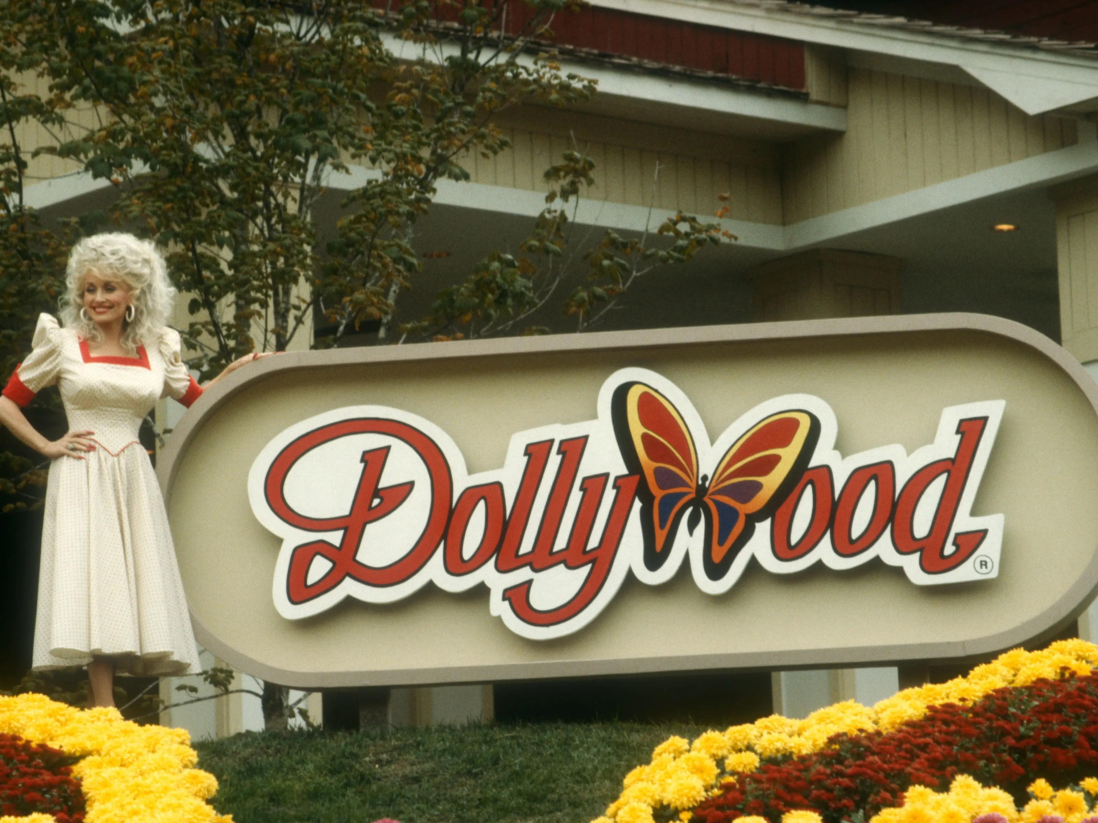 Dolly parton standing in front of the dollywood sign