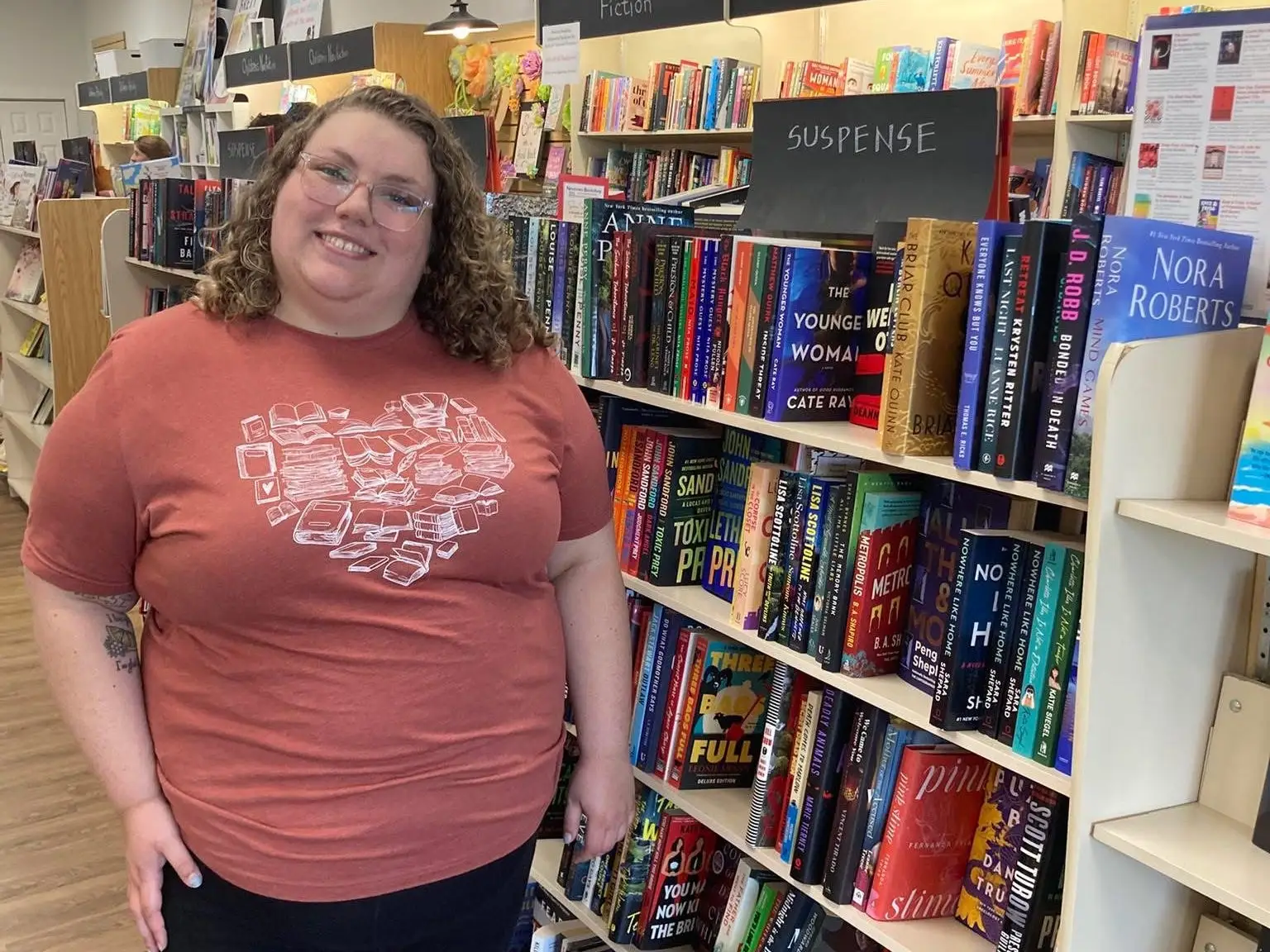 The writer is standing in front of several shelves full of books.