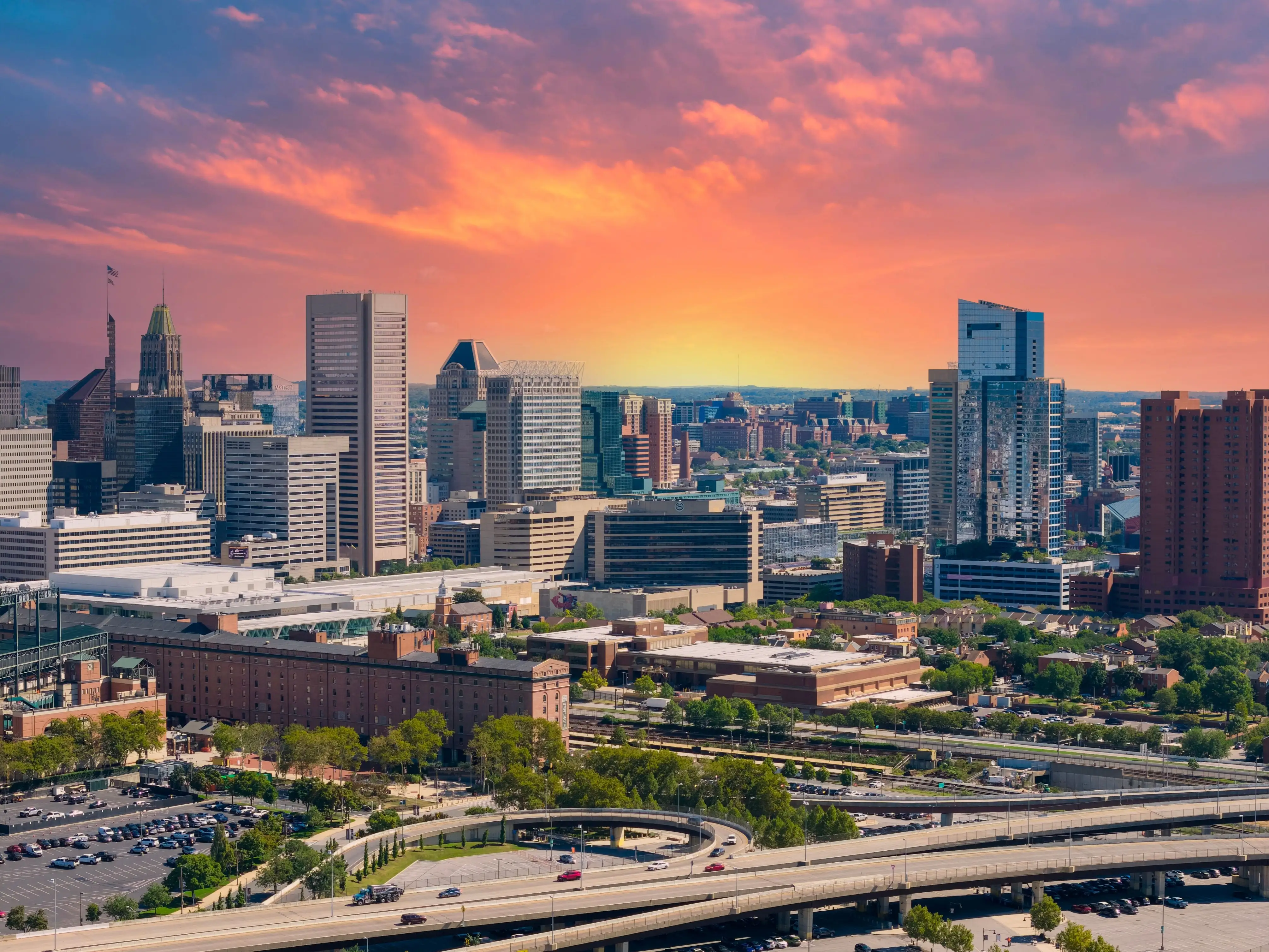 A vibrant sunset over the Baltimore cityscape featuring modern skyscrapers and urban architecture.