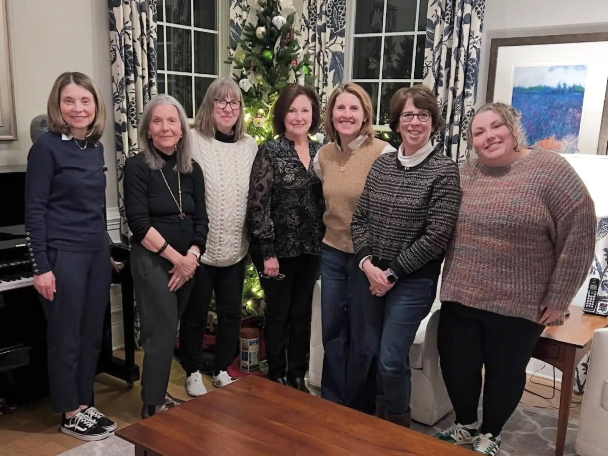 The writer and her colleagues are posing for a photo in front of a Christmas tree.