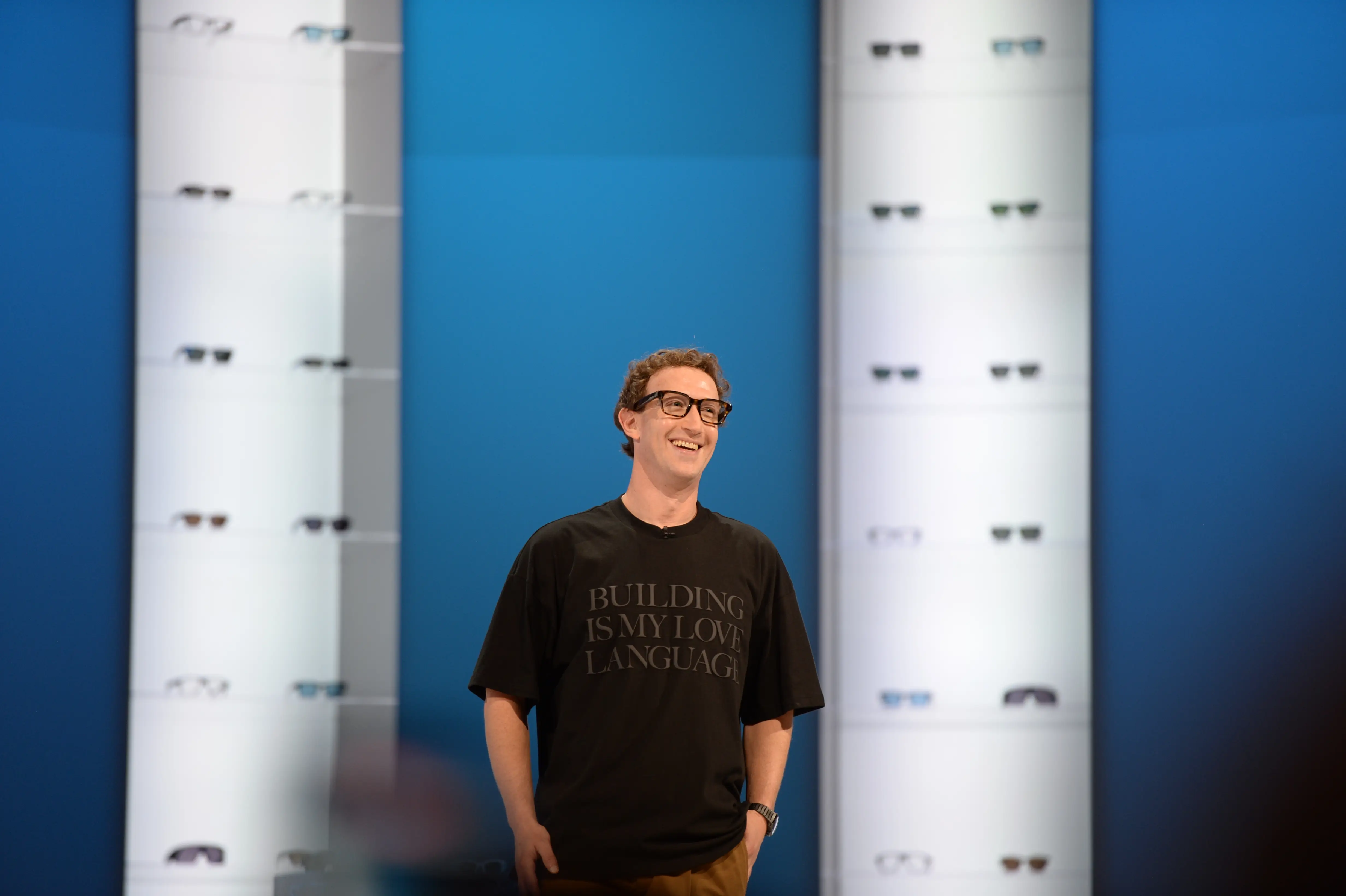 Meta CEO Mark Zuckerberg stands onstage in front of two columns of smart glasses.