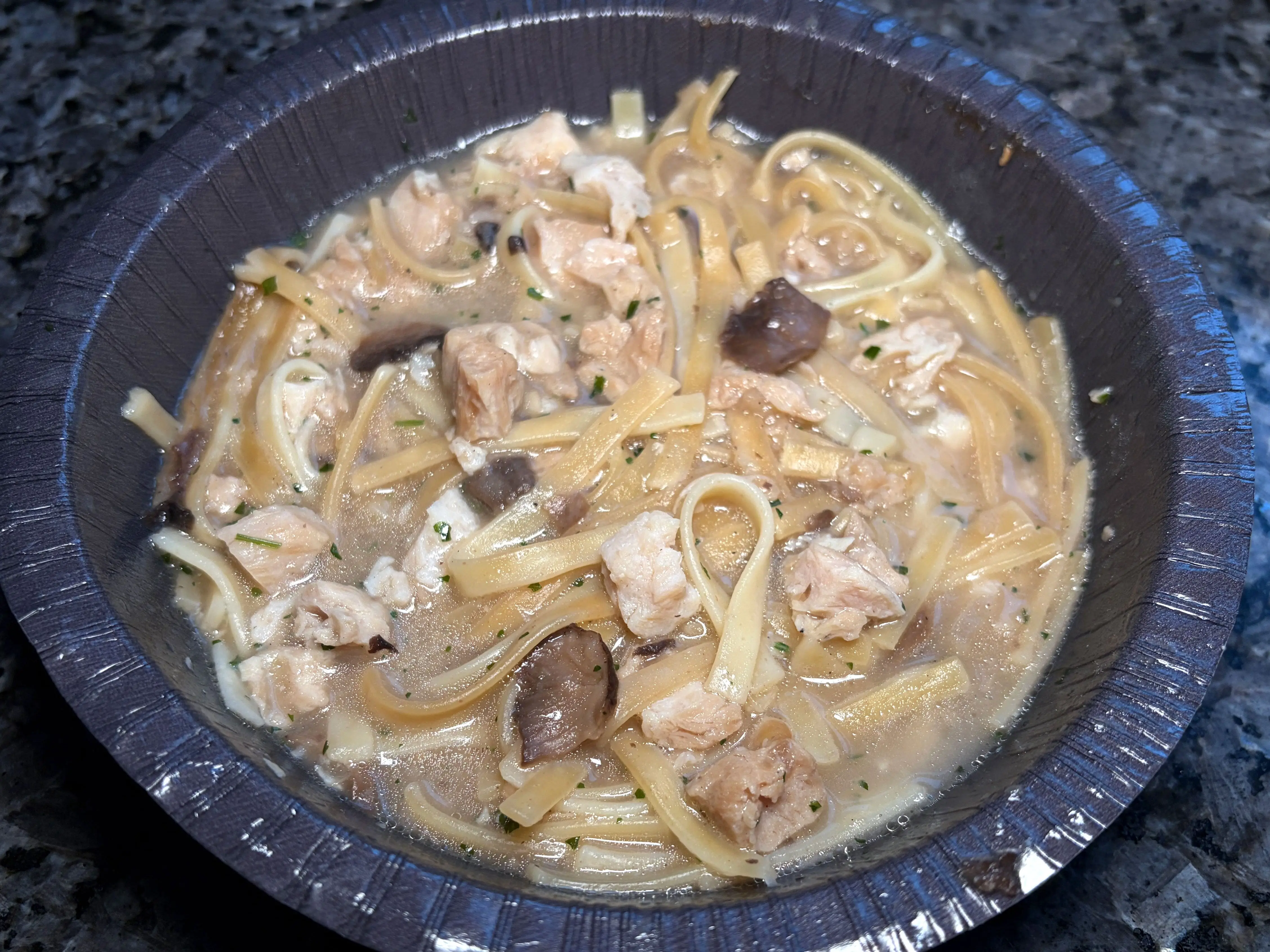 A bowl of linguine with chicken, mushrooms, and a watery sauce.
