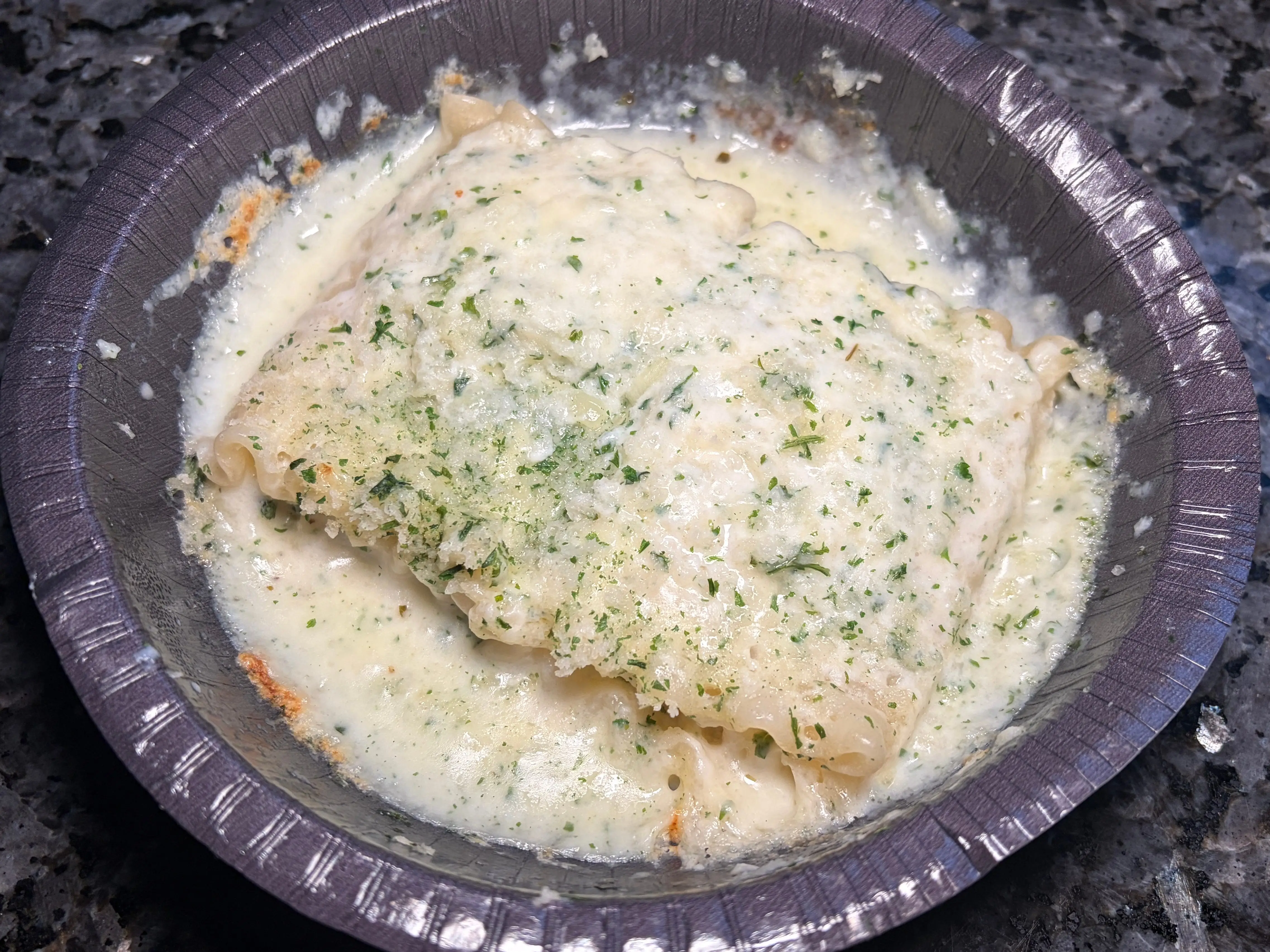 A bowl of lasagna with Alfredo sauce.