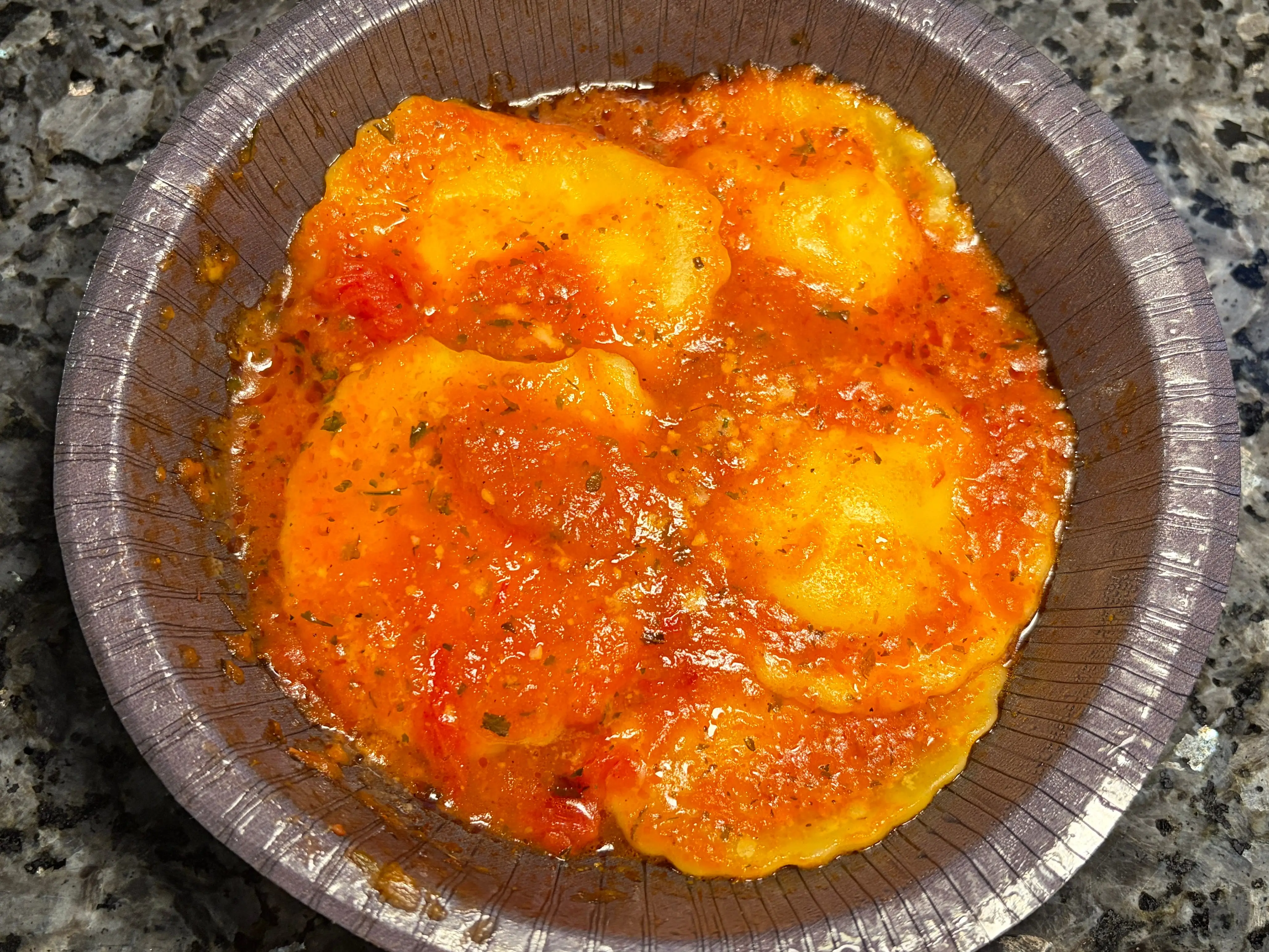 A bowl with ravioli topped with red sauce.