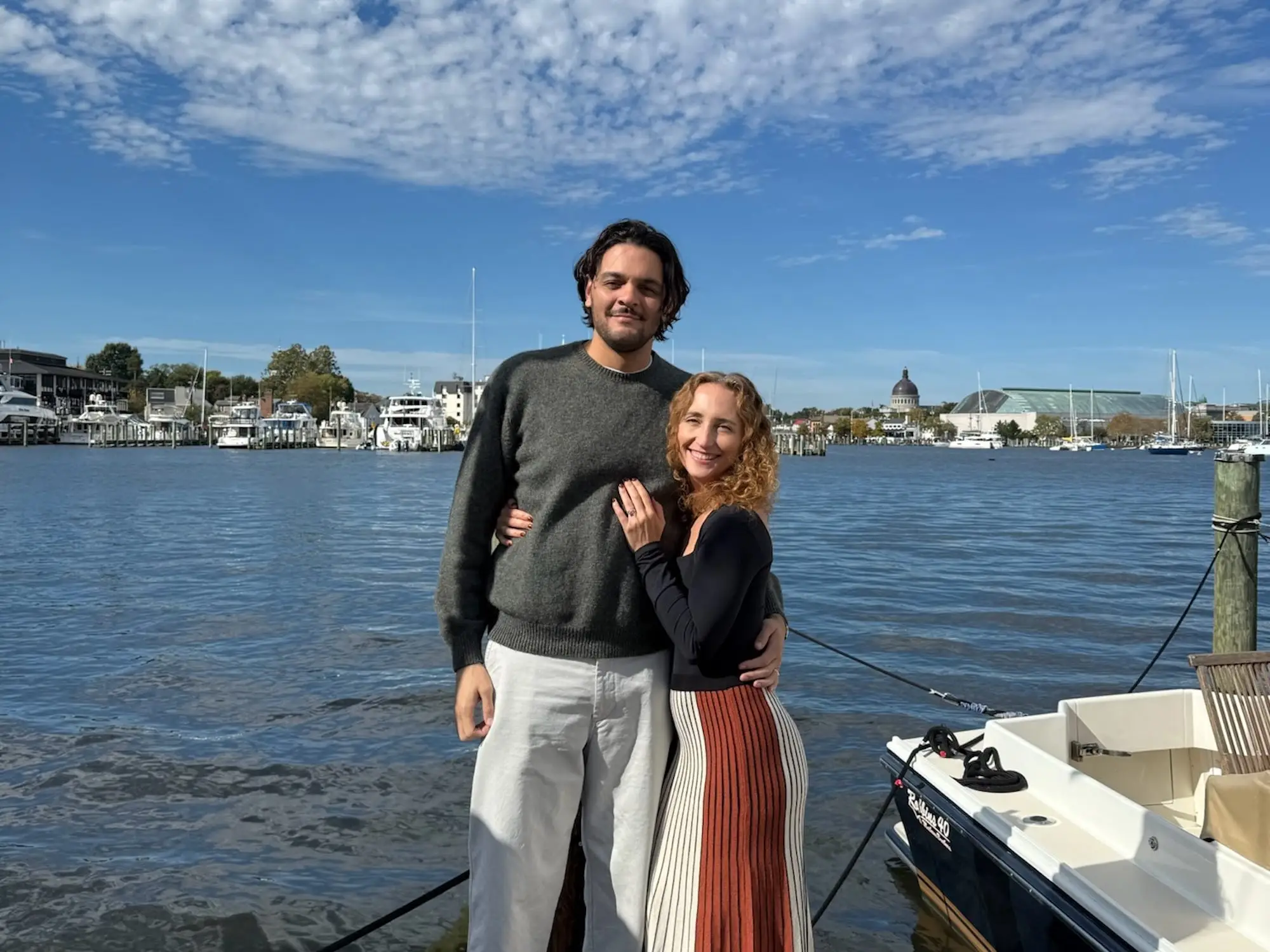 The author and her partner pose in front of a blue sky and water.