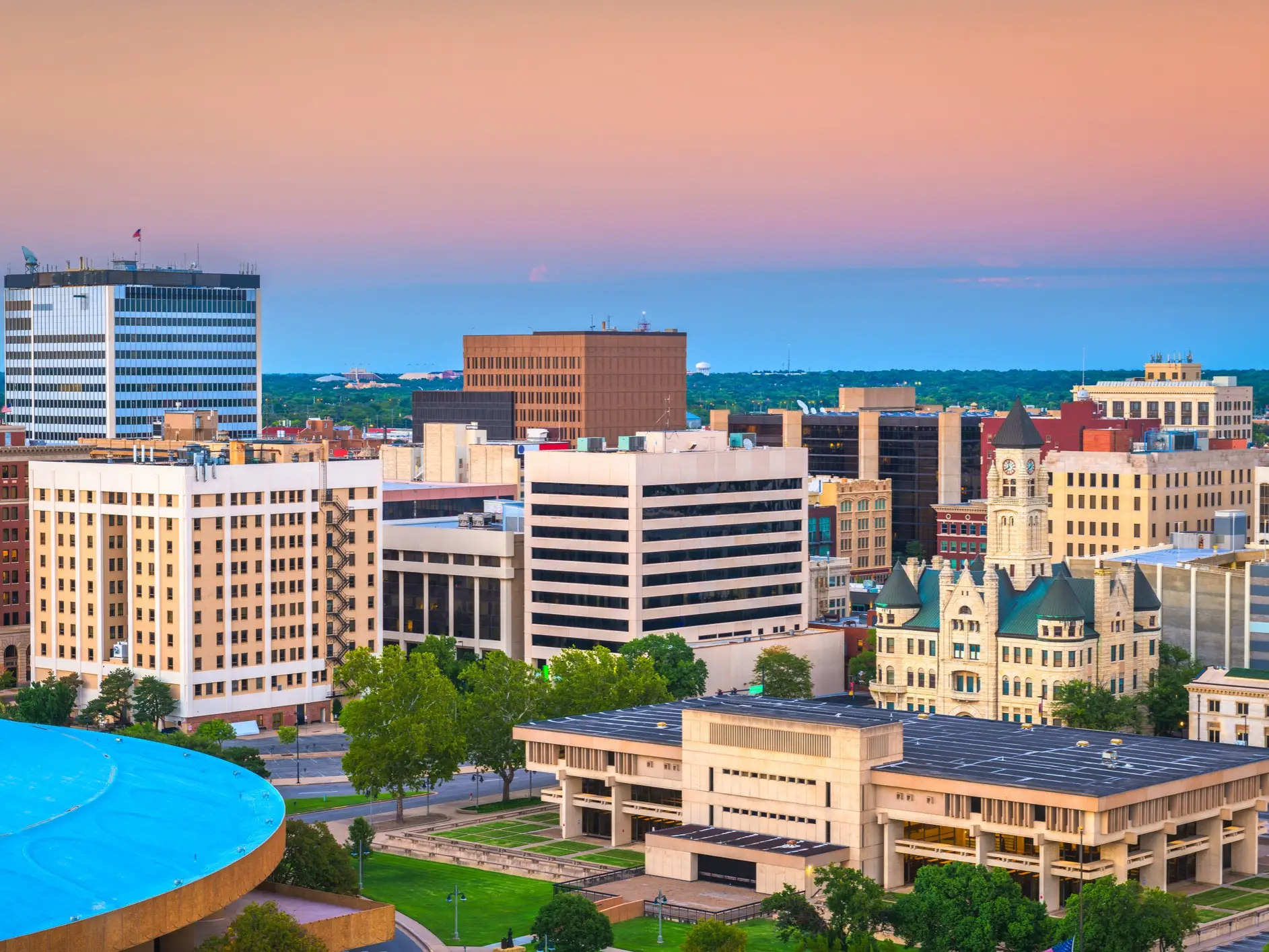 Downtown Fort Wayne skyline at dusk with the Allen County Courthouse among modern office buildings.