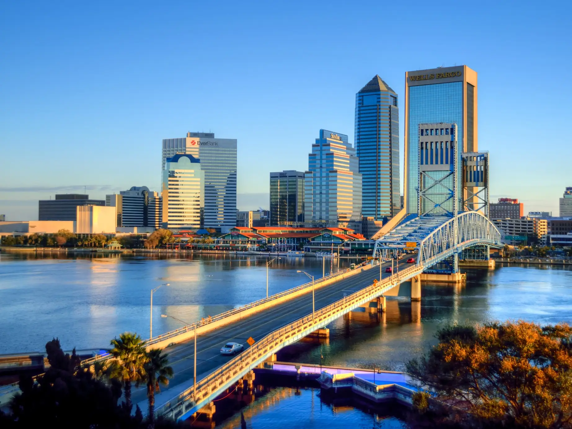 Downtown Jacksonville skyline and Main Street Bridge span the St. Johns River in warm evening light.