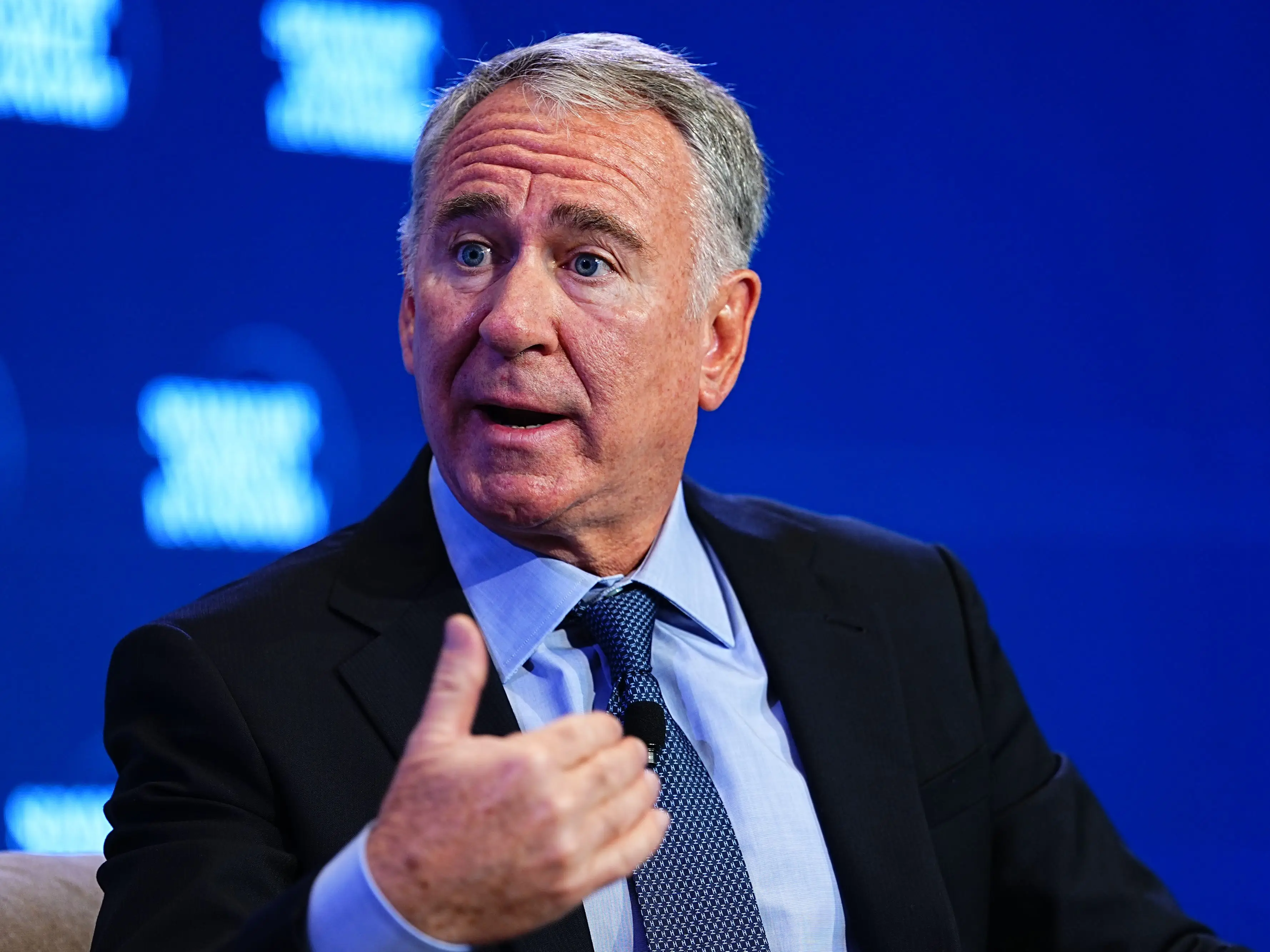Ken Griffin speaking on stage in a black suit