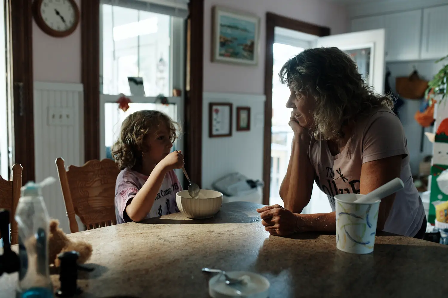 A woman is sitting at a kitchen table with her young son.