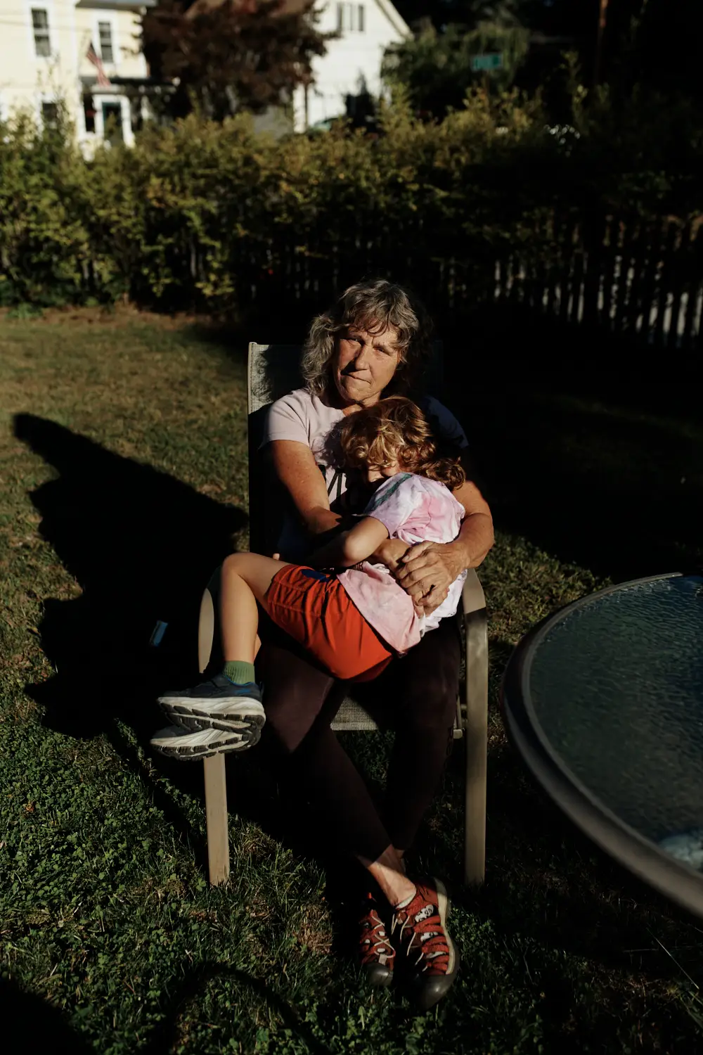 A woman sitting in a chair in her yard, cradling her son.
