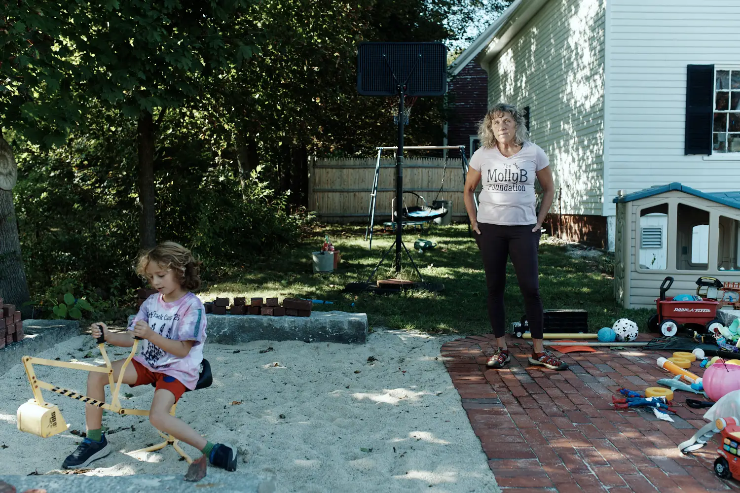 A woman looking on as her son plays in a sandbox.