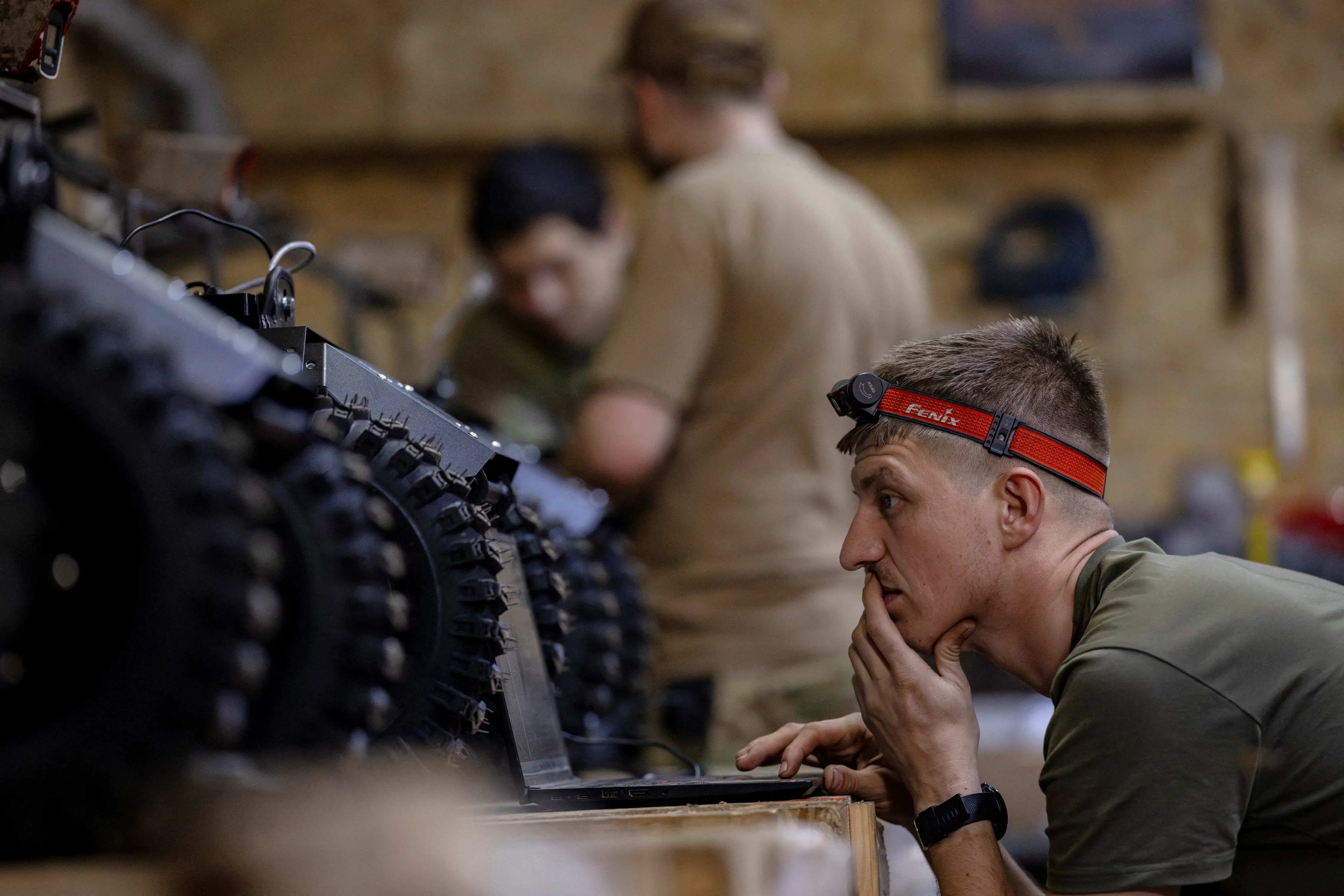 A soldier of NC13 uses a laptop connected to a ground drone.