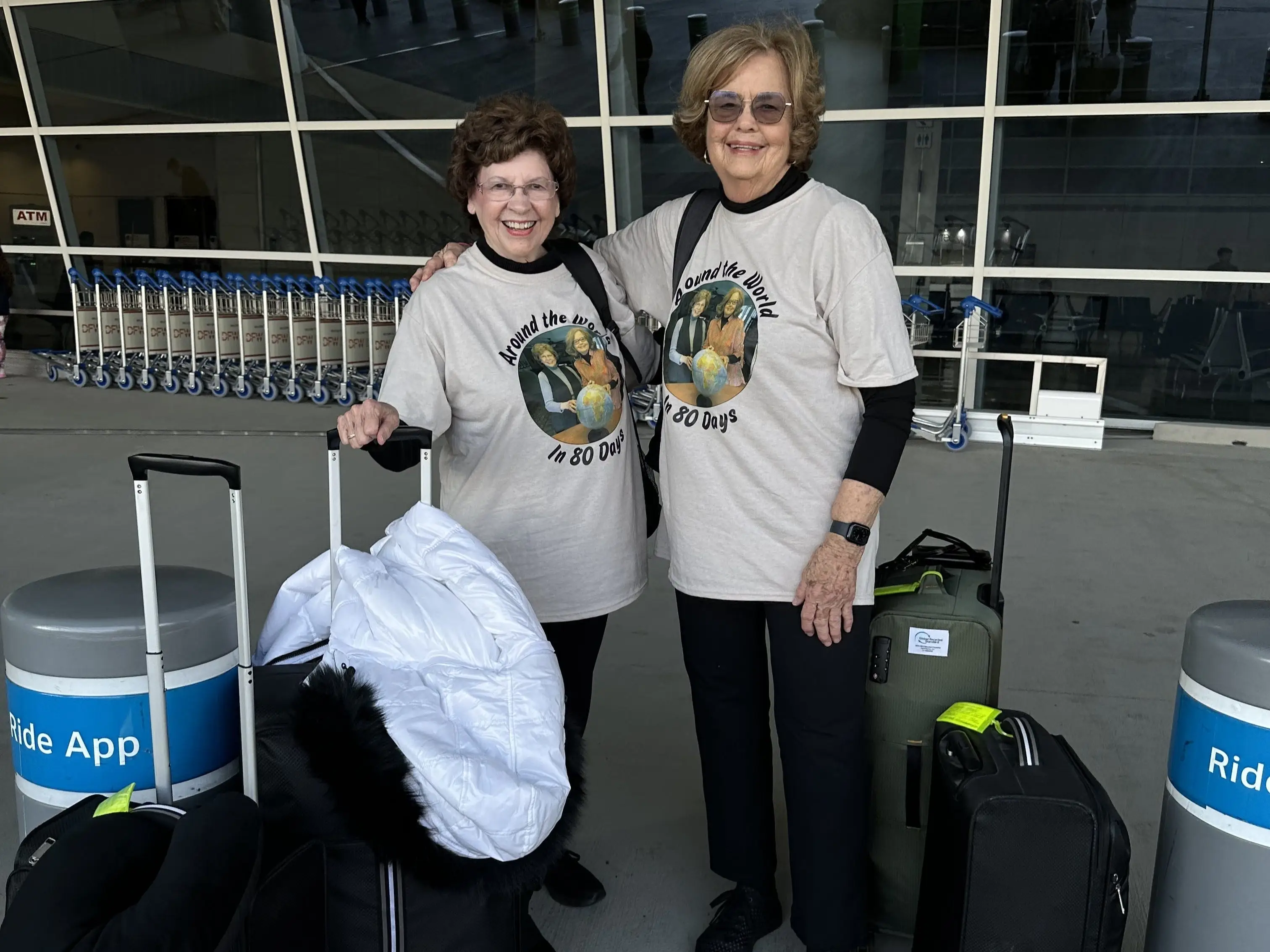 The writers in matching T-shirts stand with luggage outside an airport terminal.