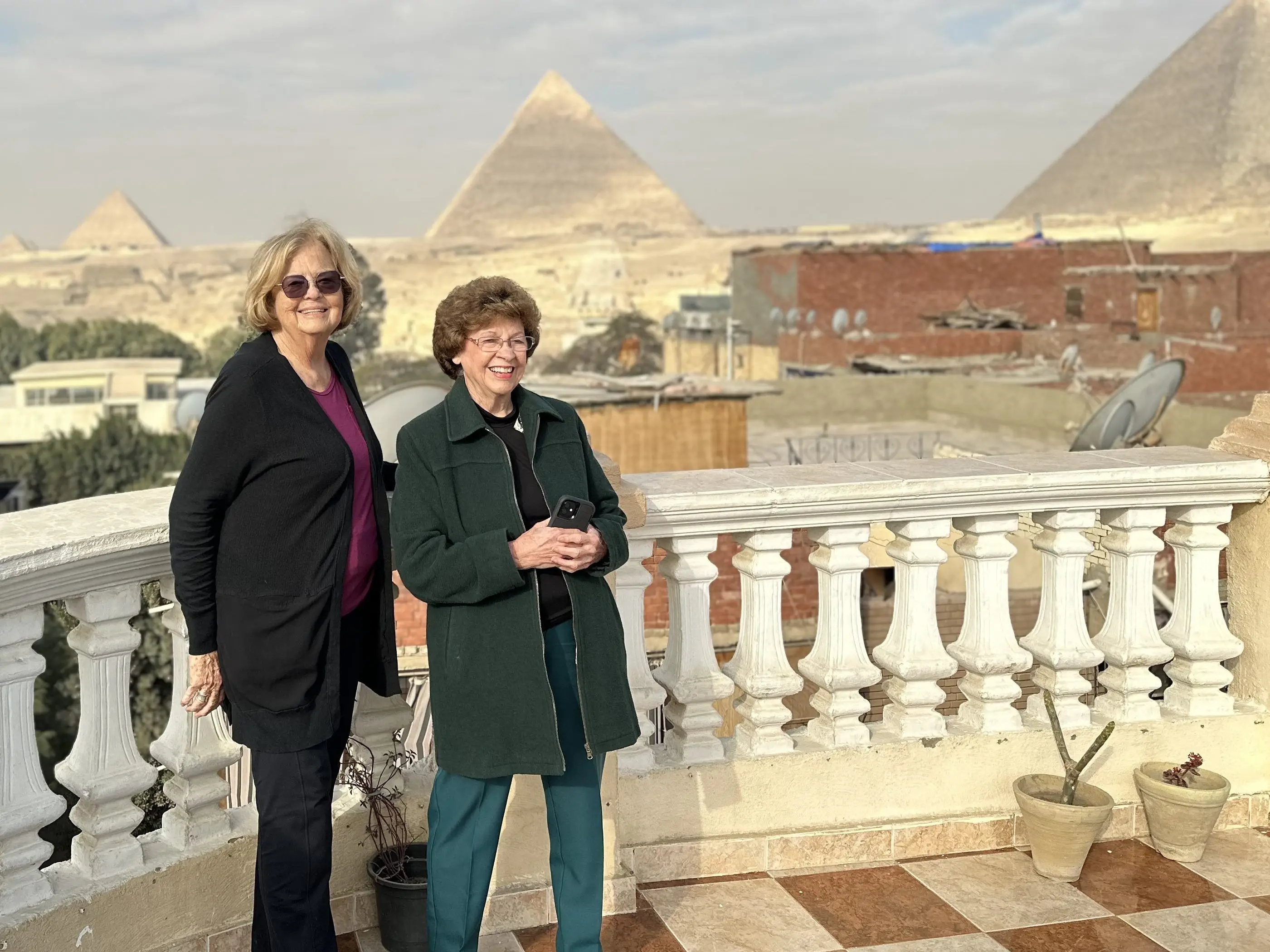 The writers stand on a tiled rooftop terrace with the Pyramids of Giza visible in the background.