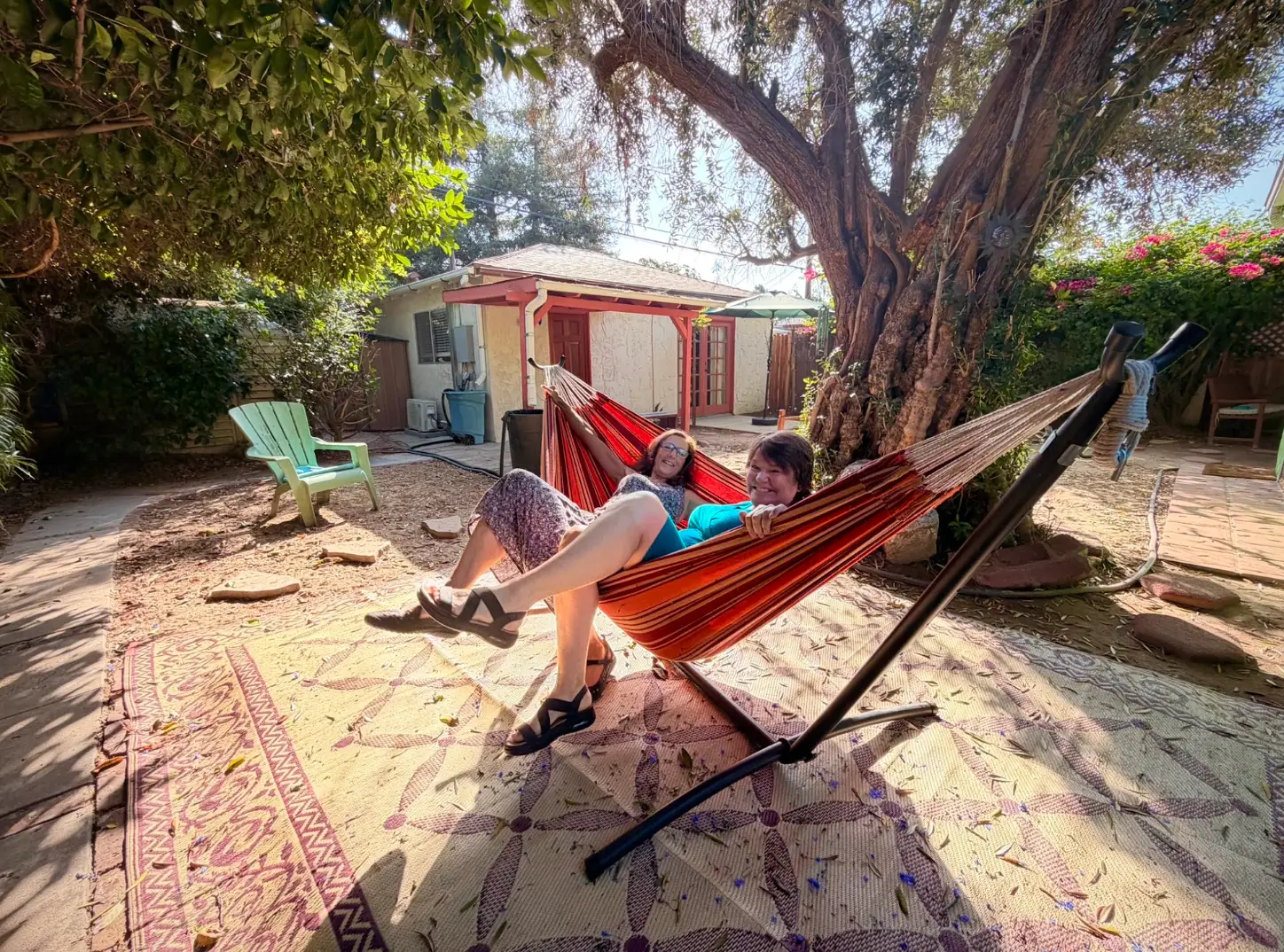 The writer and her roommate sit in a red hammock together in their yard in California.