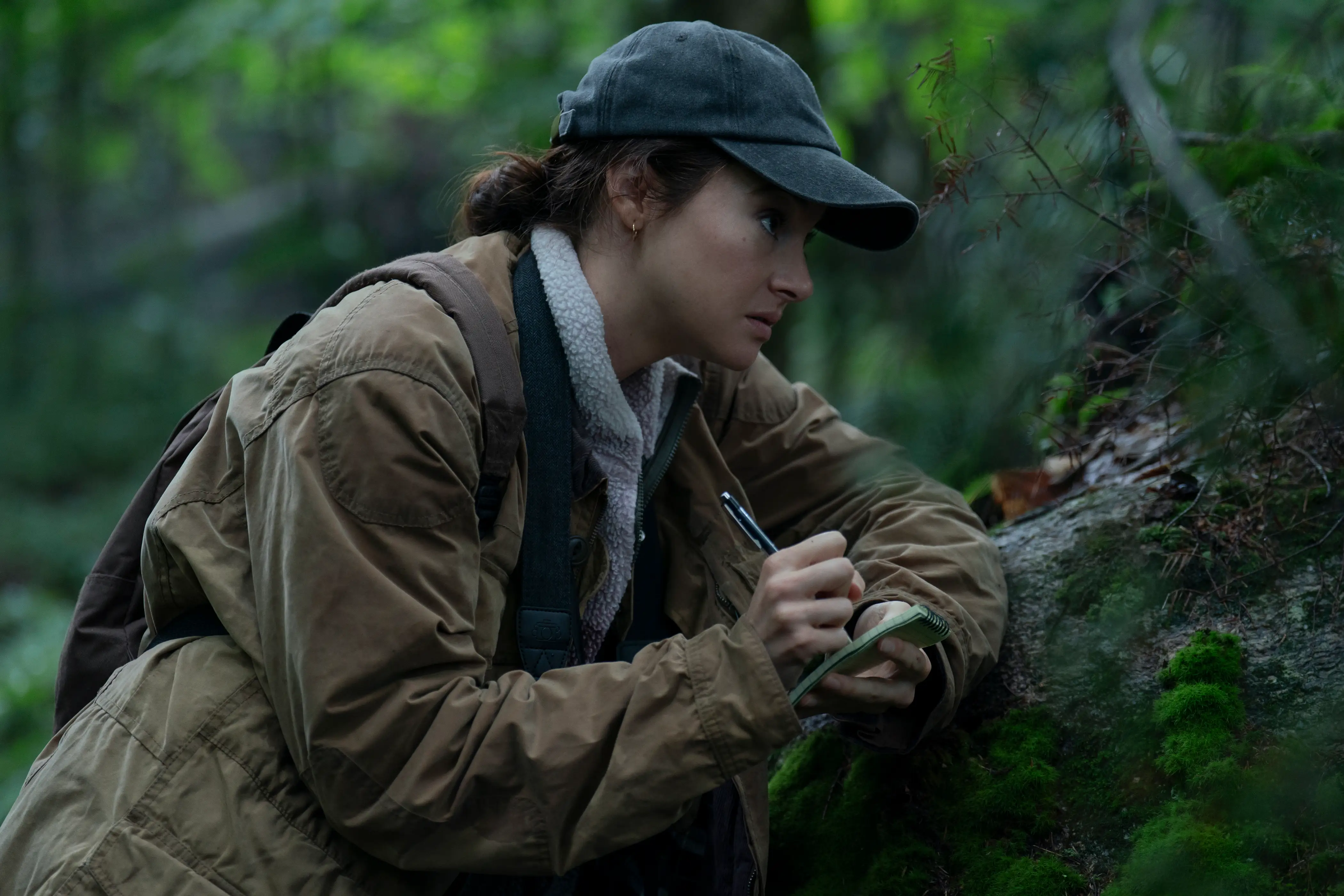 Shailene Woodley in the woods writing on a pad in Unabomber movie