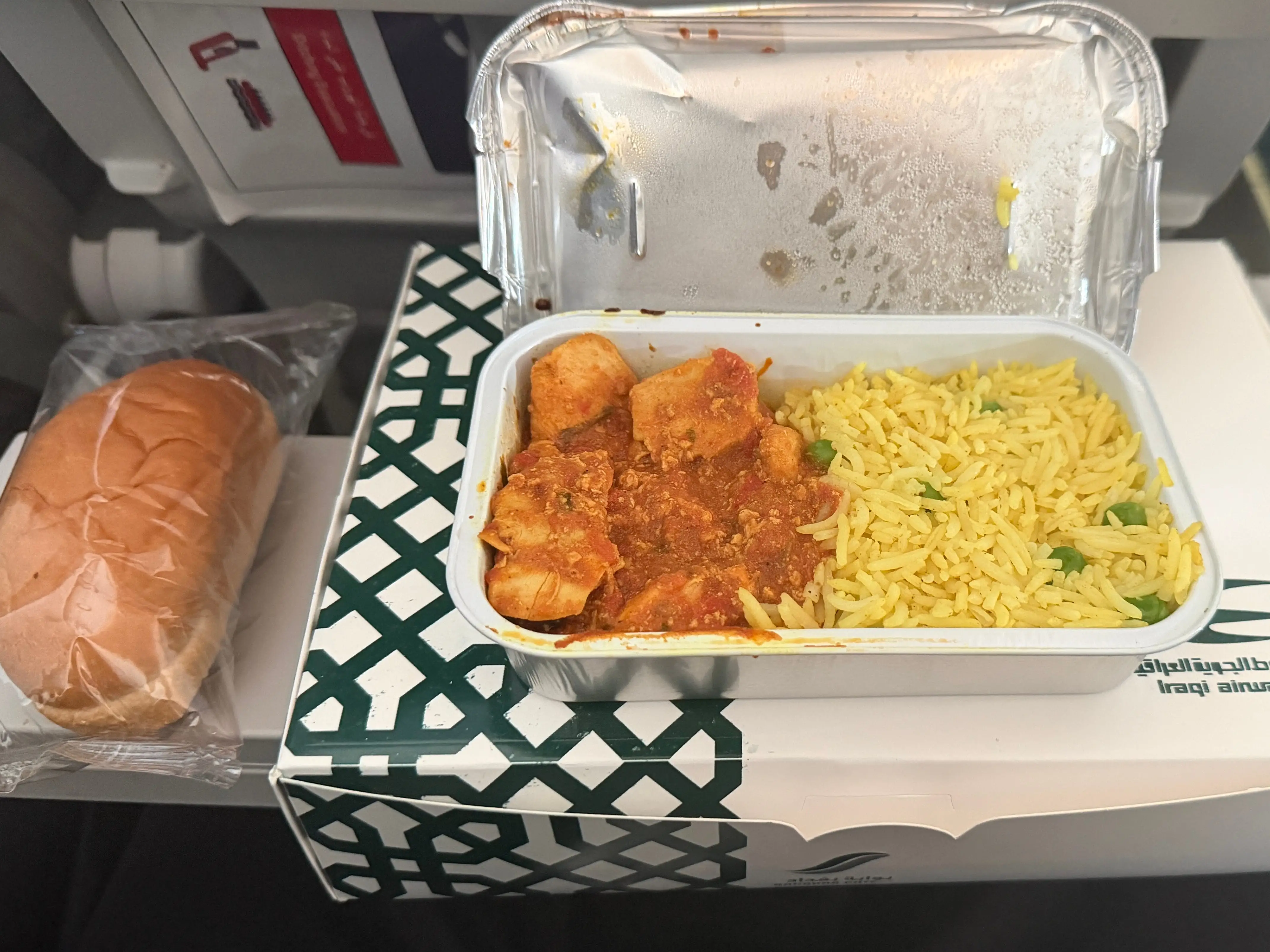 The hot meal of rice and chicken and bread on the seatback tray.