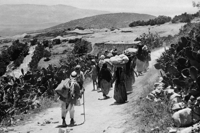 A group of people walking on a road carrying bags