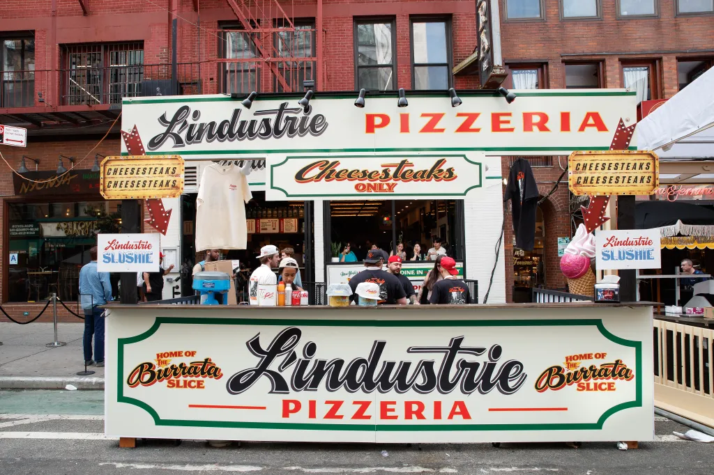 L'Industrie Pizza stand at San Genarro, featuring pizza, cheesesteaks, and burrata slices.