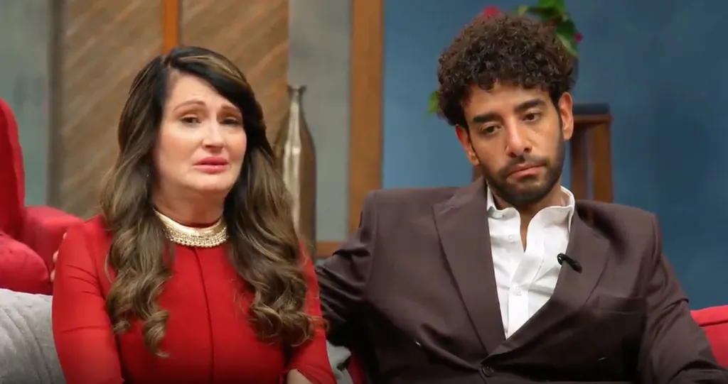 Woman in red dress crying next to a man in a brown suit.