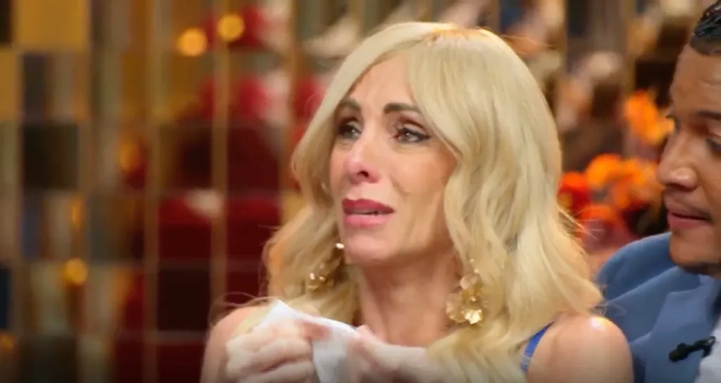 Debby cries and holds a tissue while a man sits beside her at a tell-all.