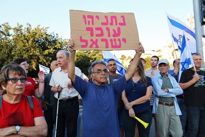 A protester holds a sign in Hebrew that says 