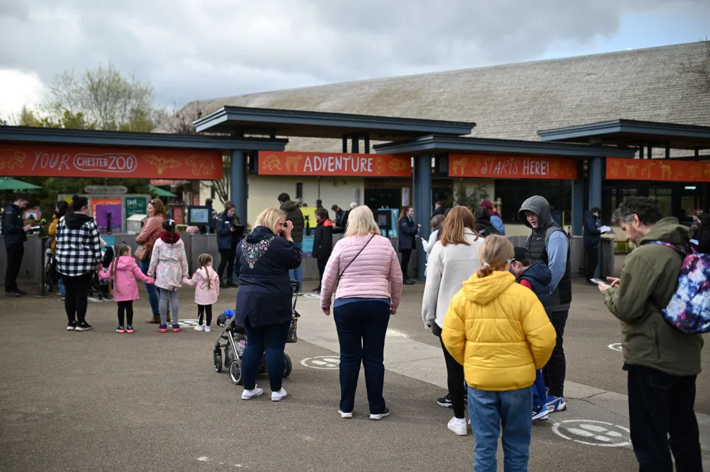 People gathered at the entrance of Chester Zoo, with an orange sign saying 