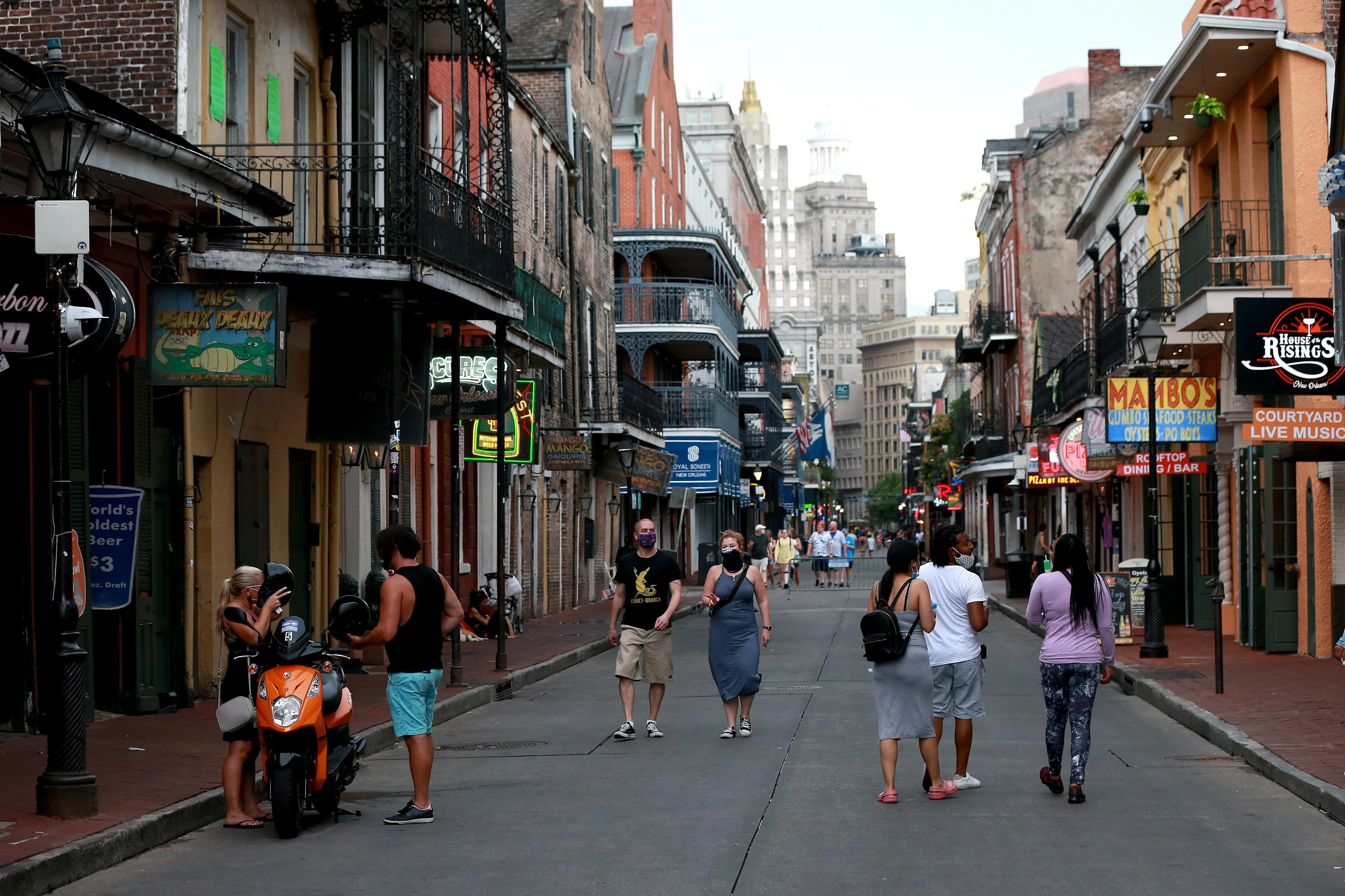 People walk along a narrow street in New Orleans’ French Quarter, lined with historic buildings, wrought-iron balconies, restaurants, bars, and neon signs People walk along a narrow street in New Orleans’ French Quarter, lined with historic buildings, wrought-iron balconies, restaurants, bars, and neon signs