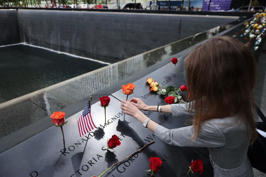 A person placing a rose on a name etched into the 9/11 Memorial.