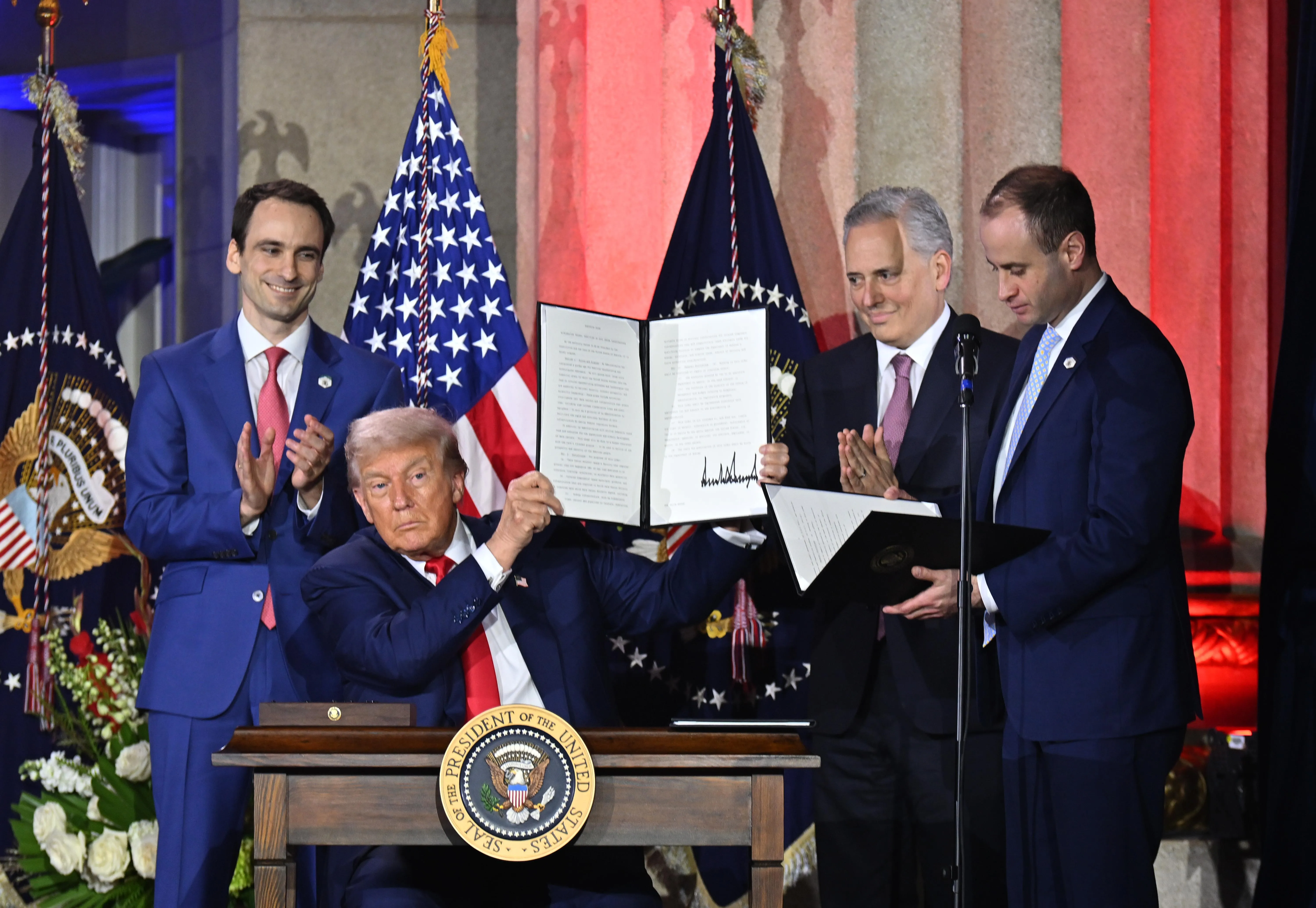 Three men standing around Trump