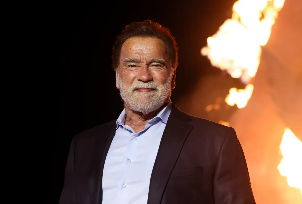 Arnold Schwarzenegger smiling with a fire in the background.